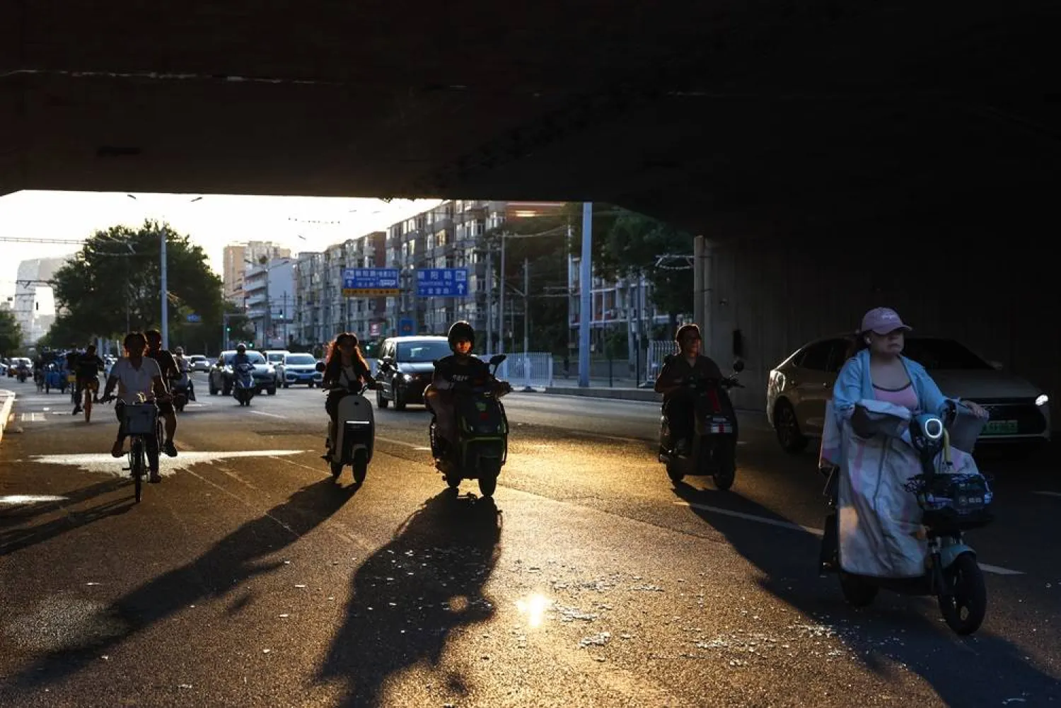 People ride scooters on a street in Beijing, China, 13 August 2025. (EPA) 