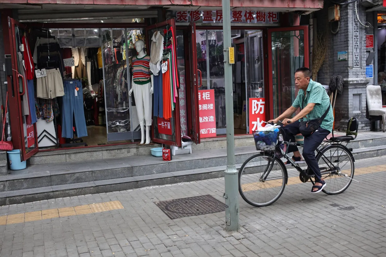 رجل على دراجة في أحد الشوارع التجارية بالعاصمة الصينية بكين (إ.ب.أ)
