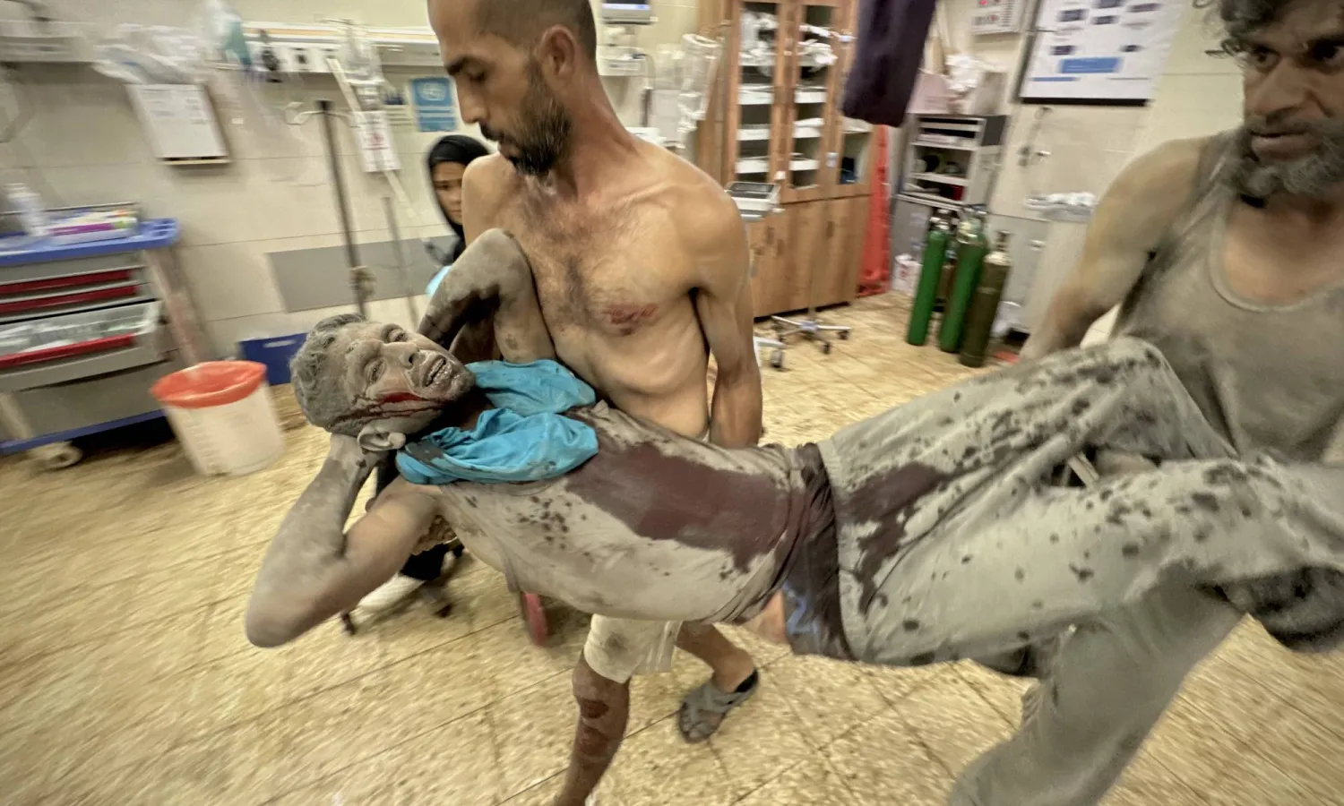 فلسطينيان ينقلان جريحاً أصيب بغارة جوية إسرائيلية على ضاحية الأمل غرب خان يونس الجمعة (د.ب.أ)