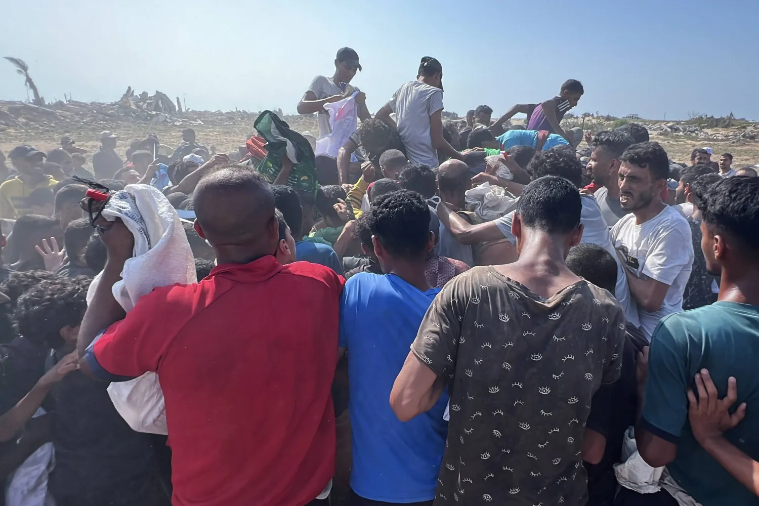 فلسطينيون يتجمعون حول حزمة مساعدات سقطت من الجو في النصيرات وسط قطاع غزة (د.ب.أ)