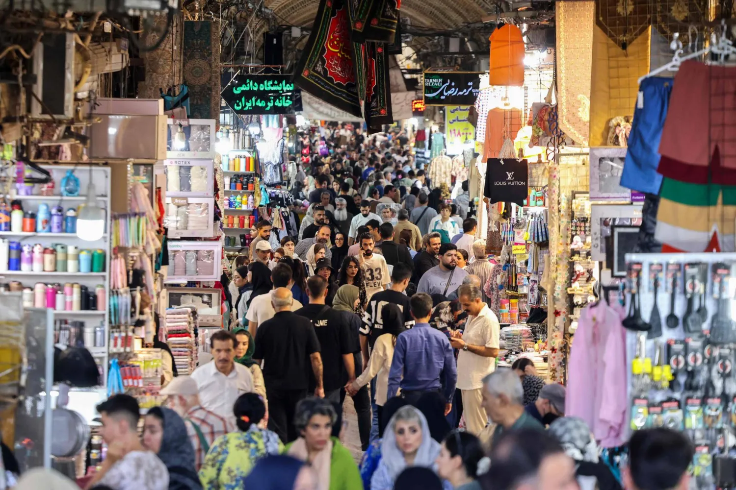 Iranians walk past shop in the Grand Bazaar in Tehran on August 13, 2025. (Photo by ATTA KENARE / AFP)
