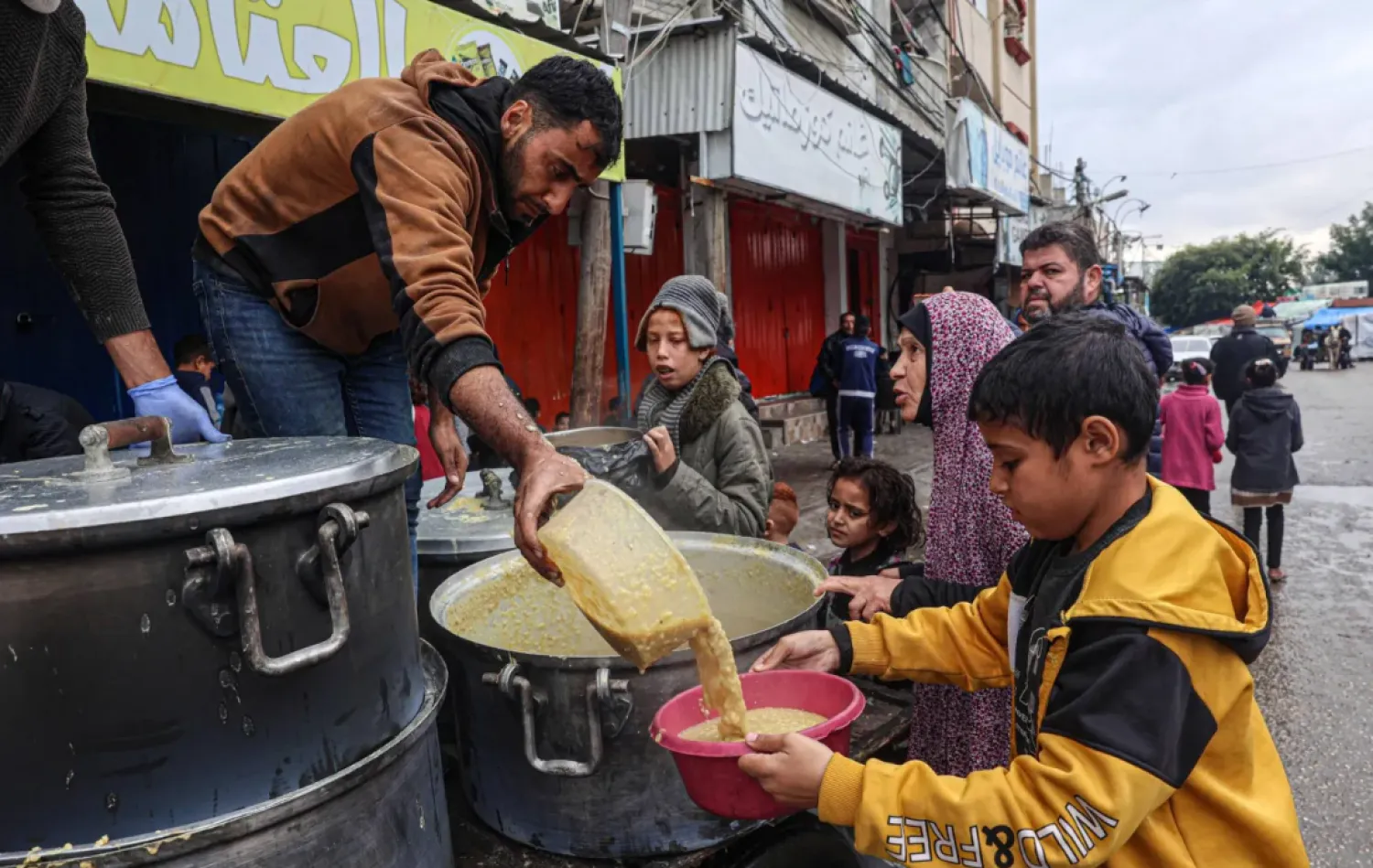 A volunteer distributes rations of red lentil soup to displaced Palestinians in Rafah in the southern Gaza Strip on February 18, 2024. (Photo by SAID KHATIB / AFP)
