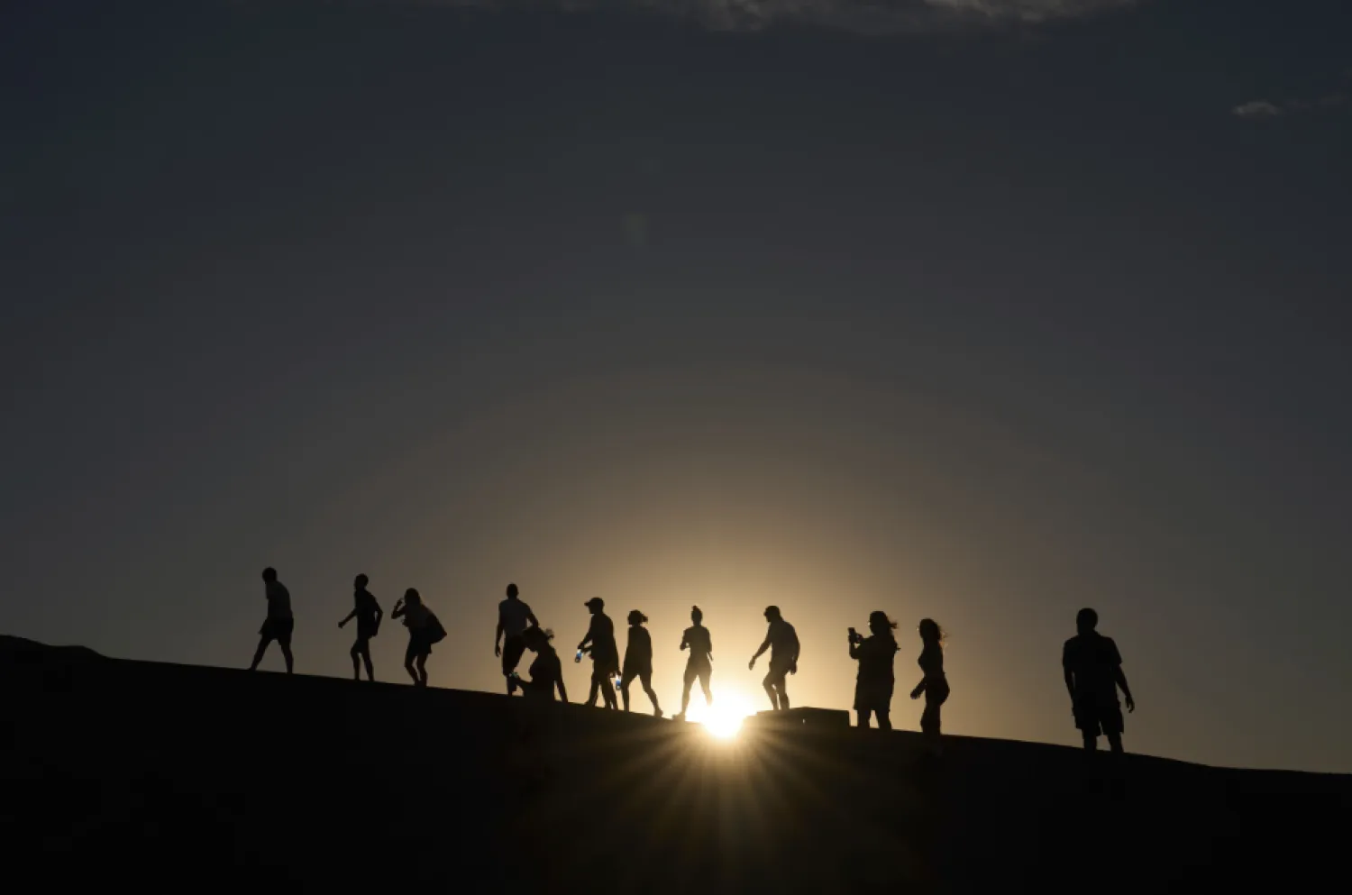 People walk up to an overlook at Zabriskie Point, Sunday, Aug. 3, 2025, in Death Valley National Park, Calif. (AP Photo/John Locher)

