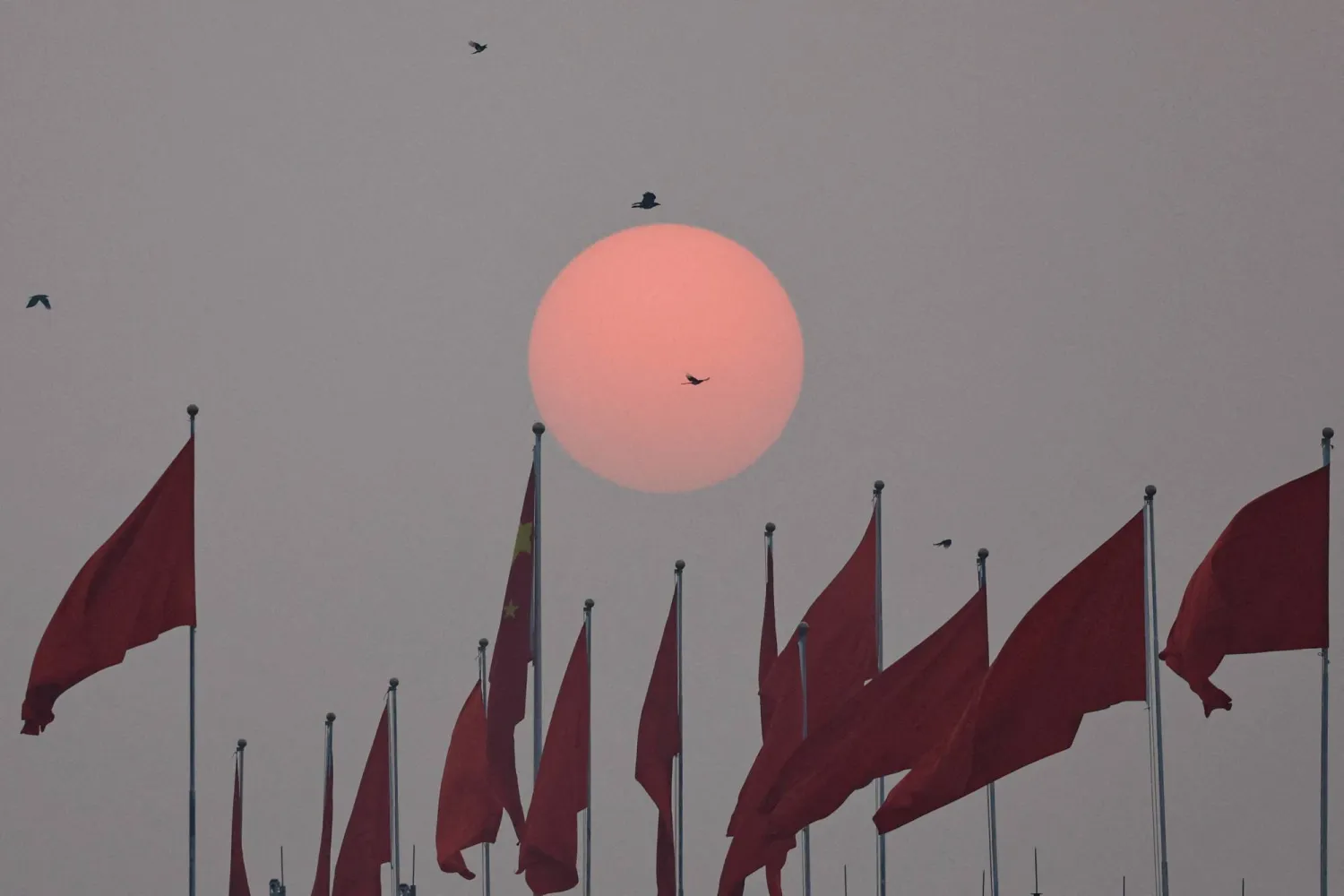 الشمس تشرق بالقرب من العلم الوطني الصيني في يوم الجلسة الختامية للمؤتمر الاستشاري السياسي للشعب الصيني (أرشيفية - رويترز)