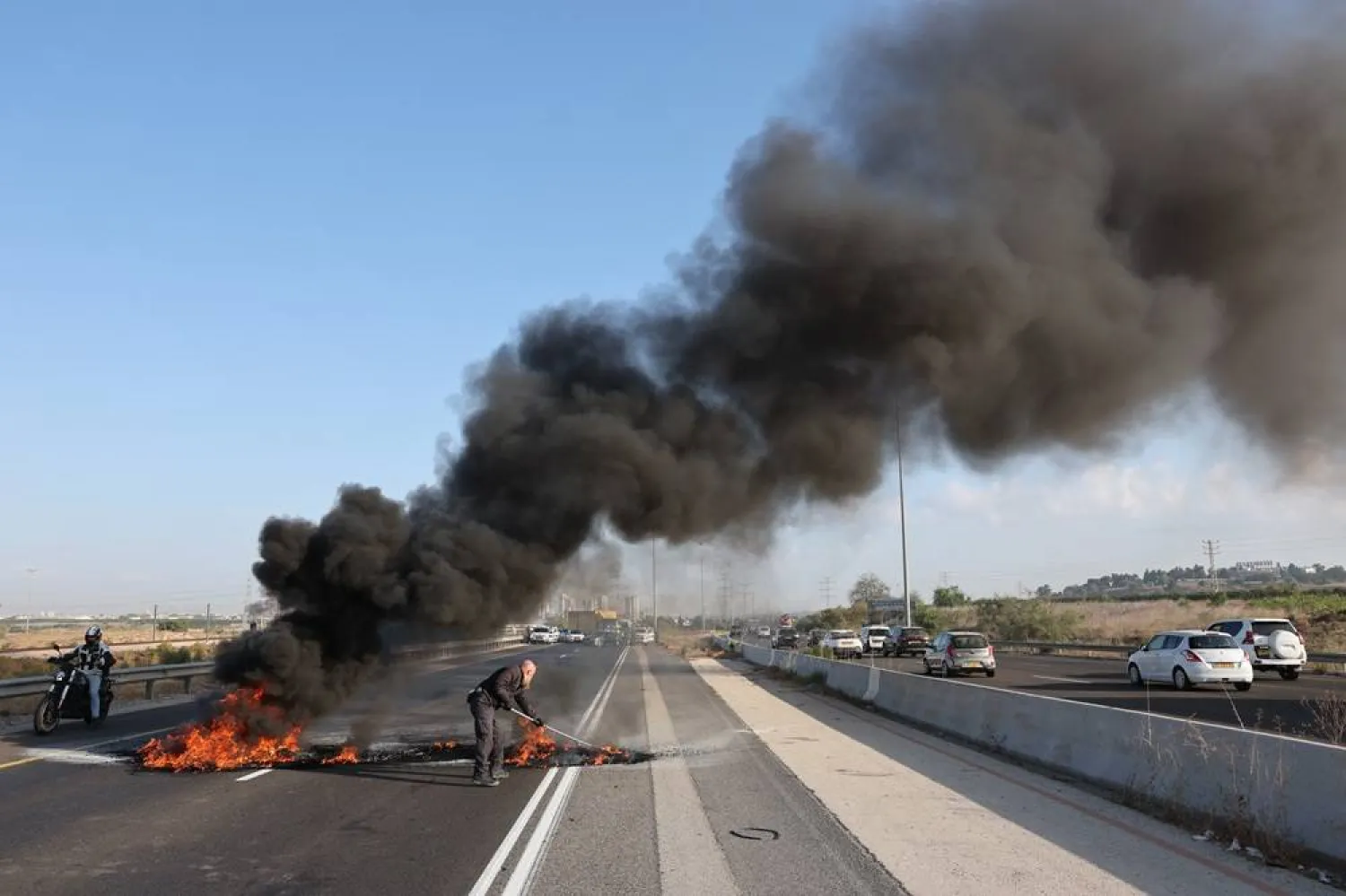 Israeli police officers work to extinguish burning tires set on fire by protesters on the main road connecting Tel Aviv and Jerusalem, Israel, 17 August 2025. (EPA)