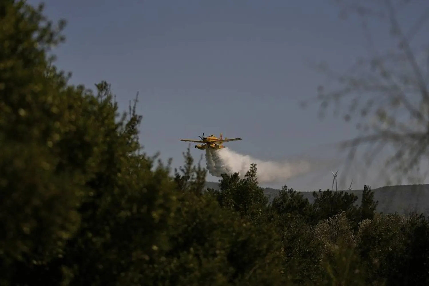 A water-bombing plane spreads water to extinguish a fire in a forested area in Guzelyeli, on the outskirts of Canakkale, northwest Türkiye, Tuesday, Aug. 12, 2025. (AP) 