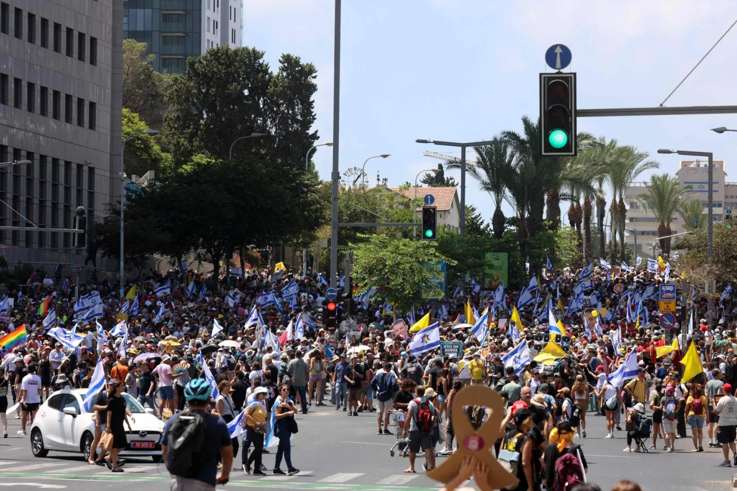 متظاهرون يرفعون أعلاماً خلال احتجاج مناهض للحكومة الإسرائيلية في تل أبيب يوم الأحد (أ.ف.ب)