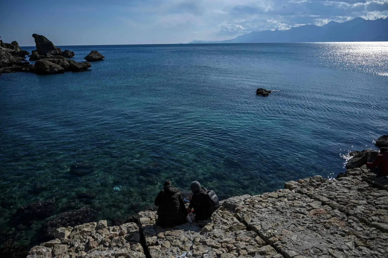 (FILES) Tourist sit by the sea at Kaleici marina in Antalya, in southern Türkiye on March 12, 2022. (Photo by Ozan KOSE / AFP)