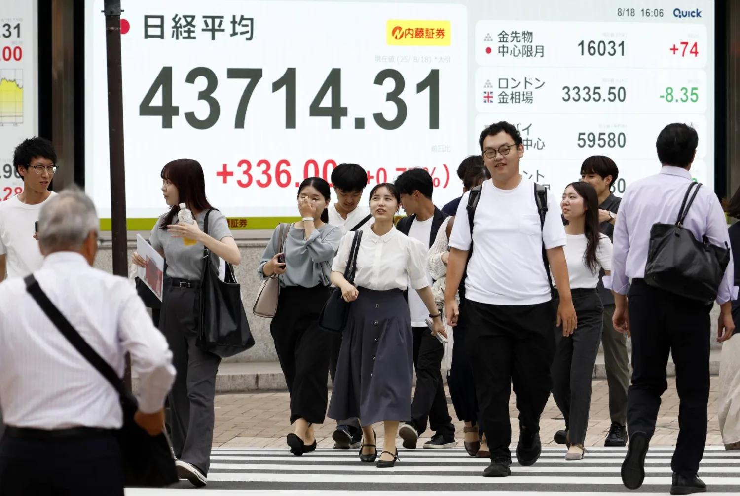 مشاة بأحد شوارع العاصمة اليابانية طوكيو يمرون أمام لوحة إلكترونية تعرض حركة الأسهم في البورصة التي وصلت إلى مستويات قياسية جديدة يوم الاثنين (إ.ب.أ)