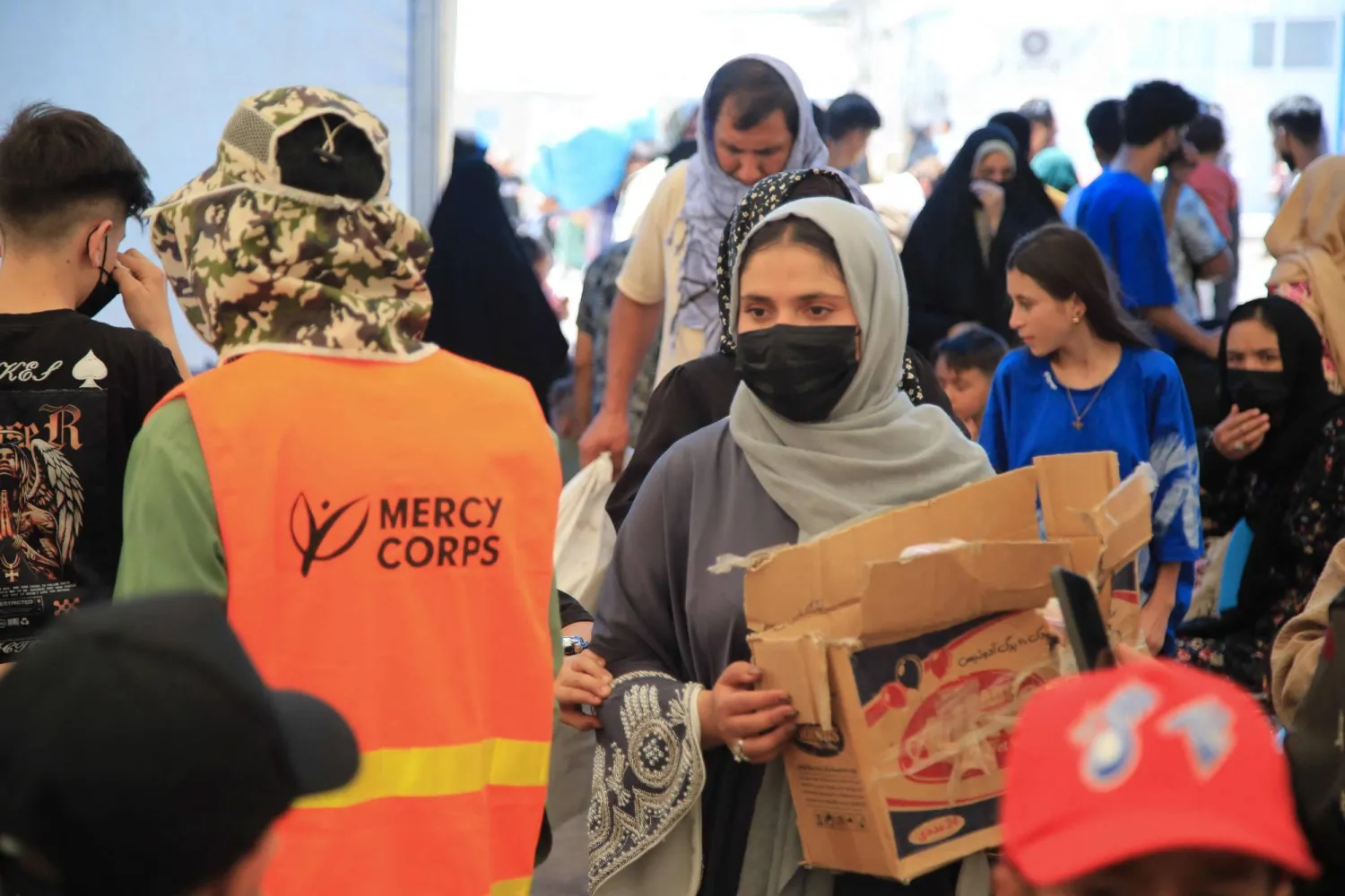 فاطمة رضائي (يمين في الأمام) متطوعة أفغانية توزع إمدادات الإغاثة على المهاجرين الأفغان الواصلين حديثاً والمُرحَّلين من إيران عند معبر «إسلام قلعة» الحدودي بولاية هرات في 24 يوليو 2025 (أ.ف.ب)