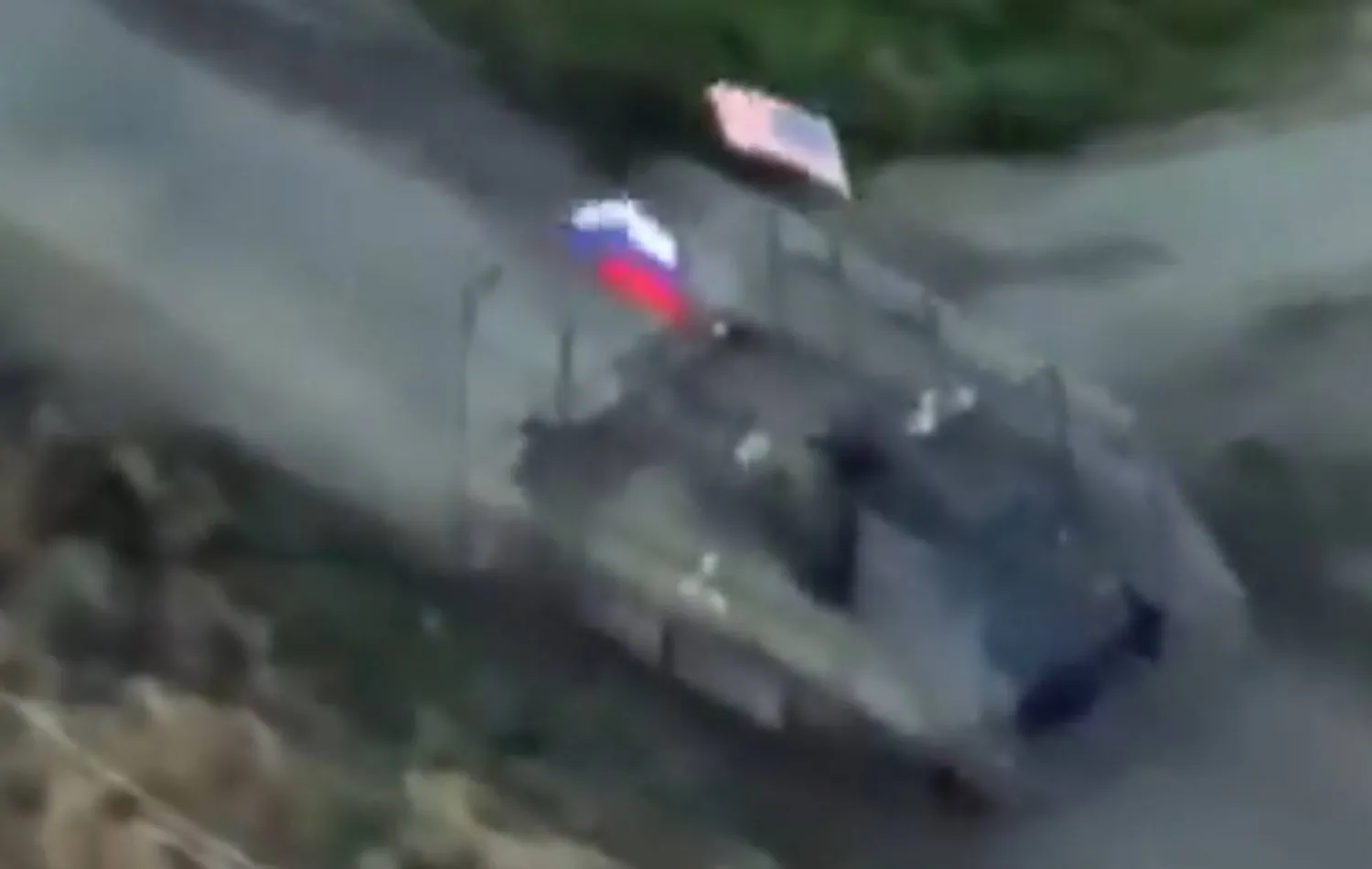 لقطة من فيديو يُظهر مركبة مدرعة تتقدم رافعةً العلمين الروسي والأميركي 