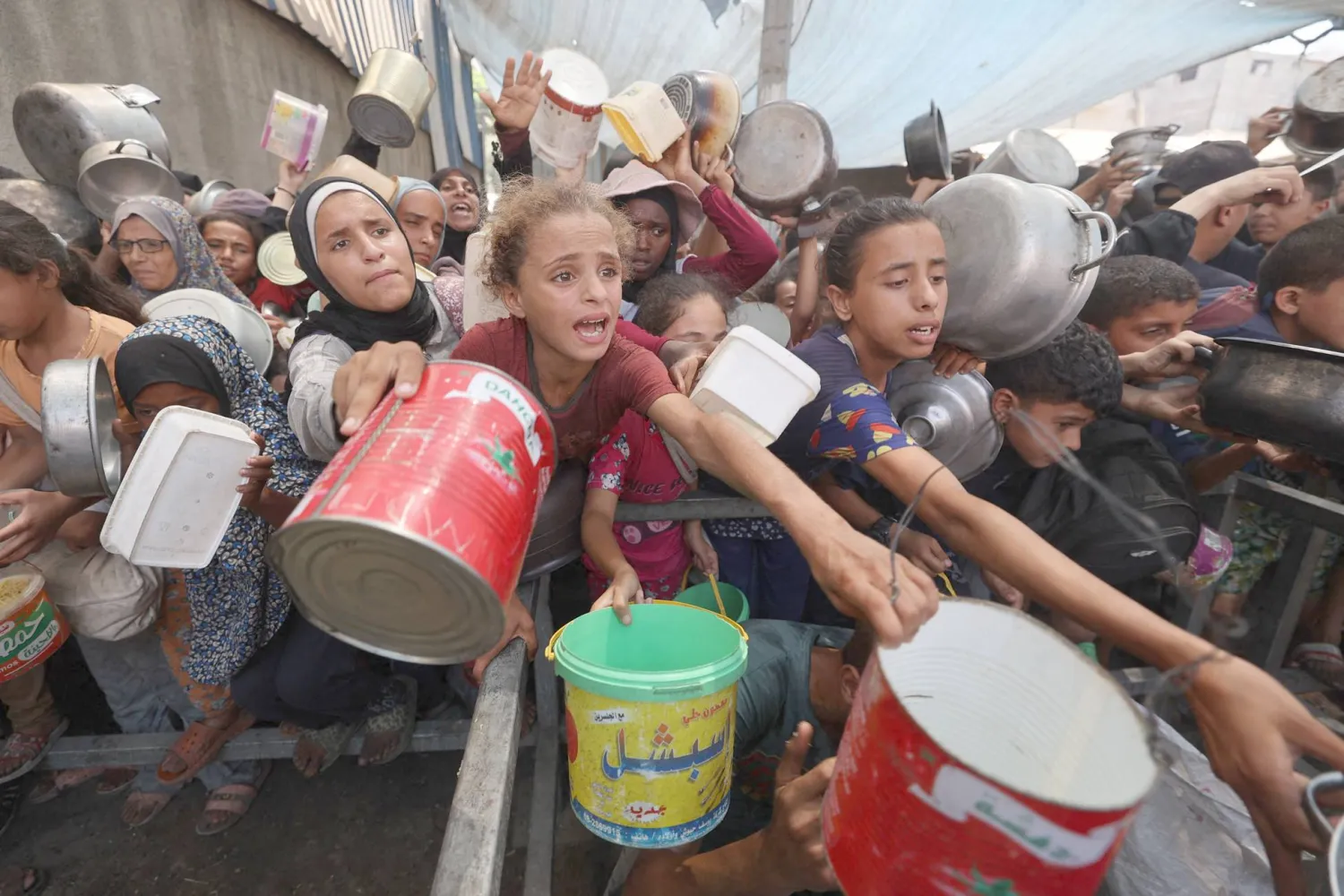 Palestinians gather to receive cooked meals from a food distribution center in the Nuseirat refugee camp in the central Gaza Strip on August 18, 2025.  (Photo by Eyad BABA / AFP)