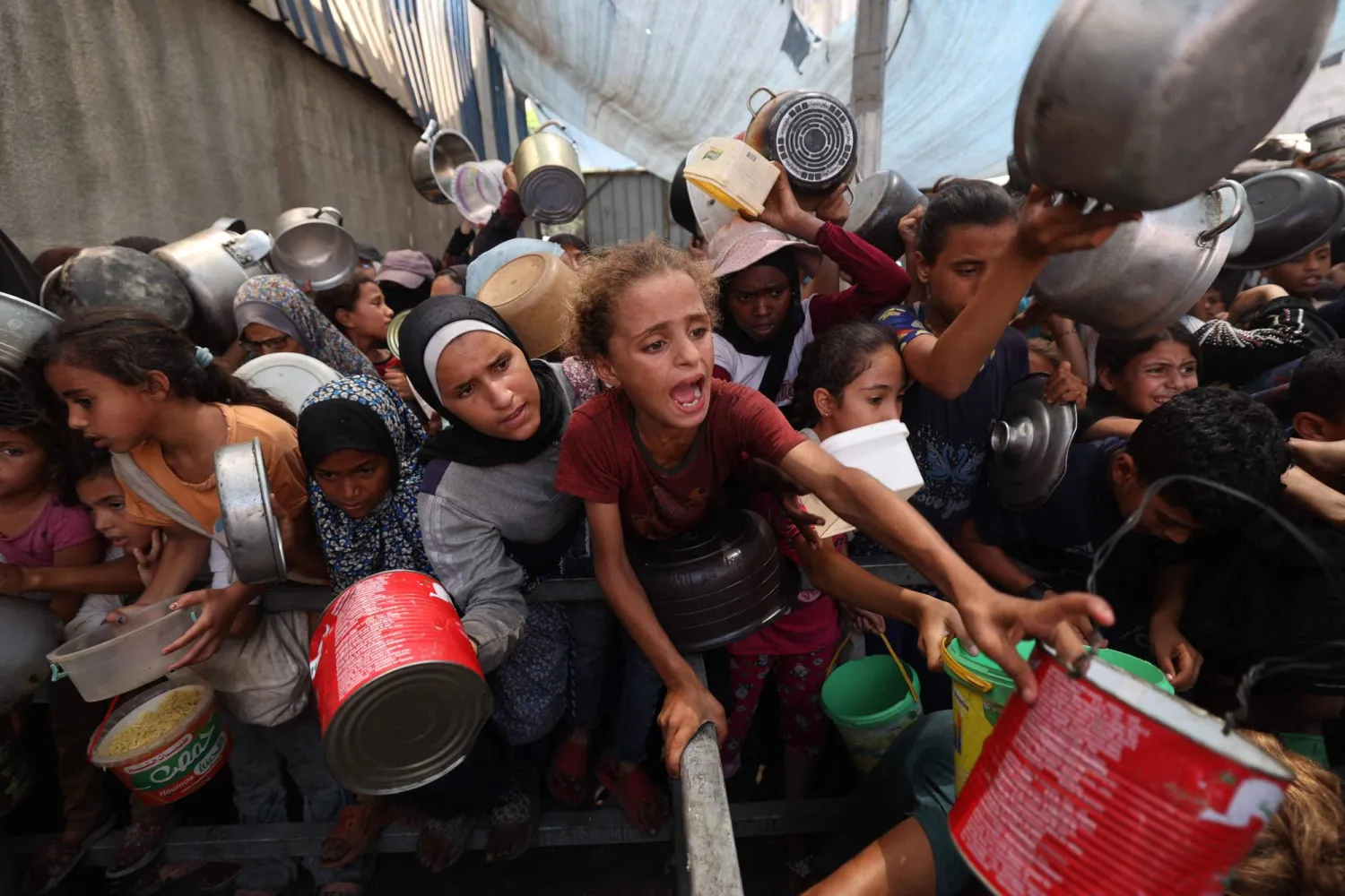 فلسطينيون يتجمعون لتسلم وجبات طعام من مركز توزيع أغذية في مخيم النصيرات للاجئين وسط قطاع غزة (أ.ف.ب)