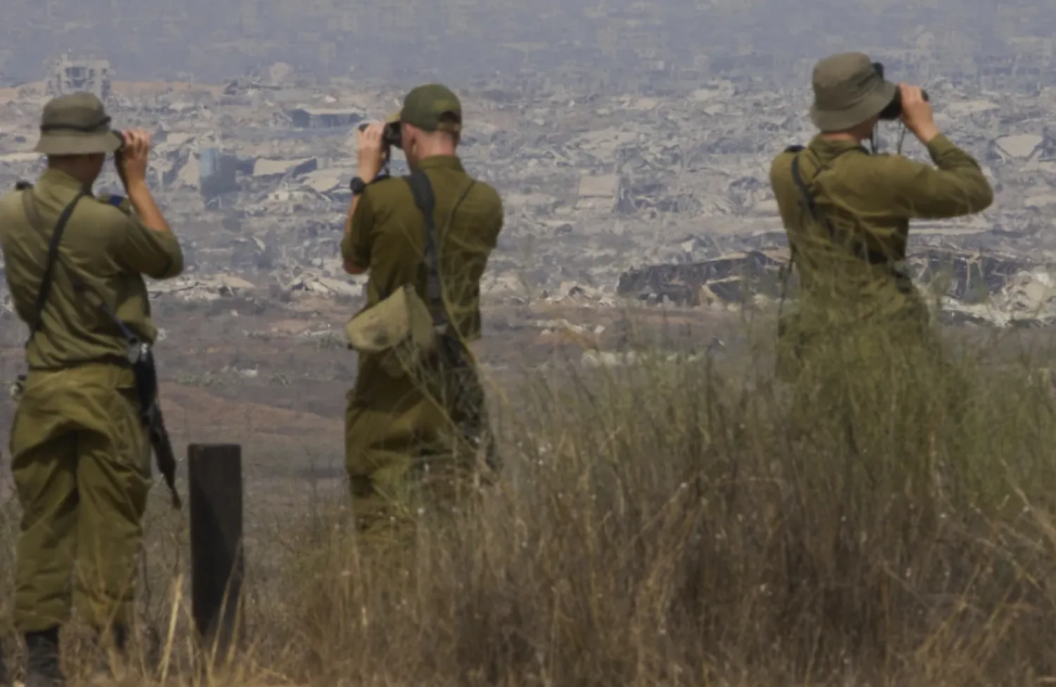 Israeli soldiers uses binoculars to look at damaged buildings in the Gaza Strip, from southern Israel, Wednesday, Aug. 13, 2025. (AP Photo/Ariel Schalit)

