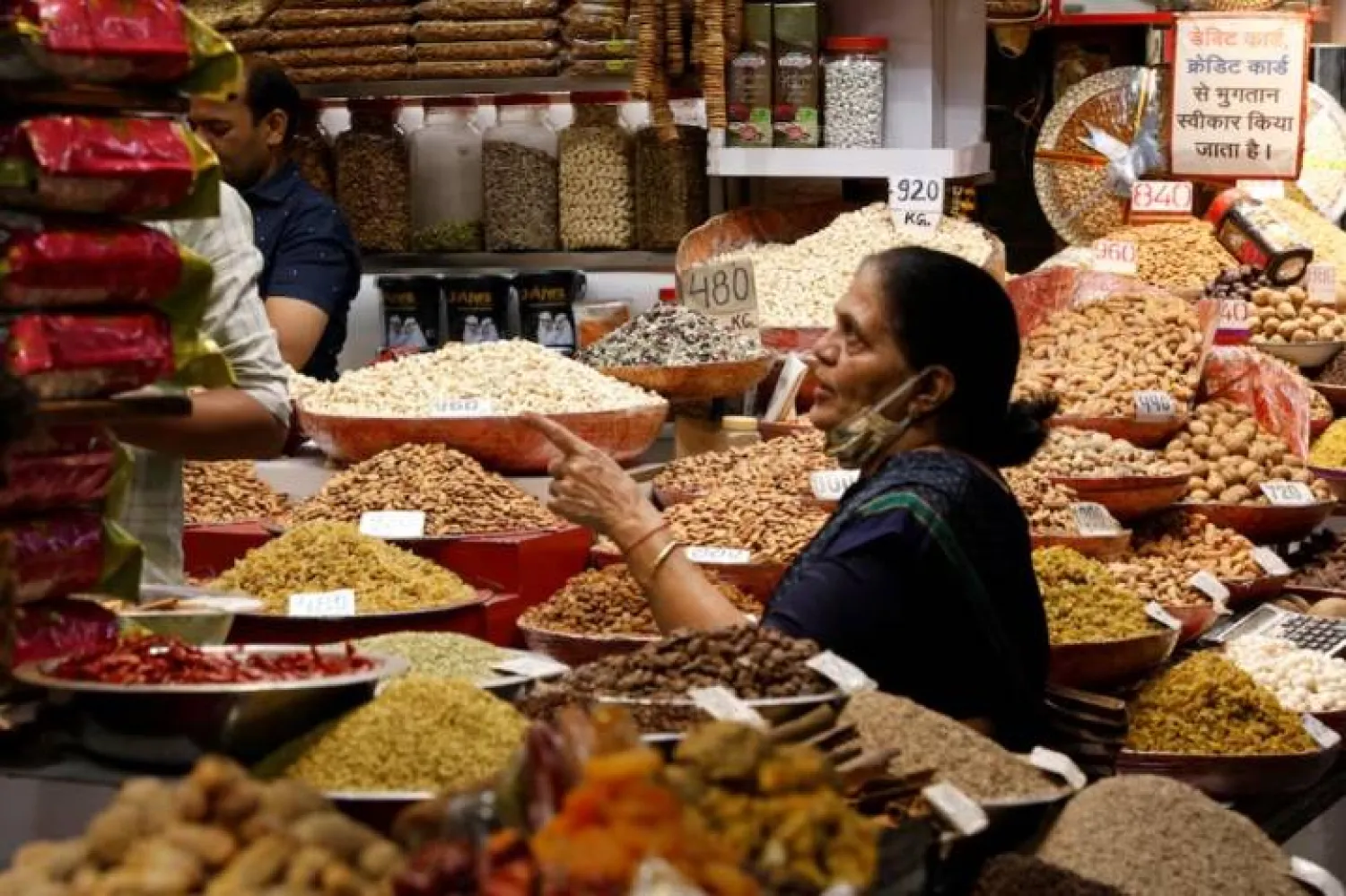 امرأة تشتري المكسرات من متجر في سوق الجملة بالأحياء القديمة في نيودلهي (رويترز)