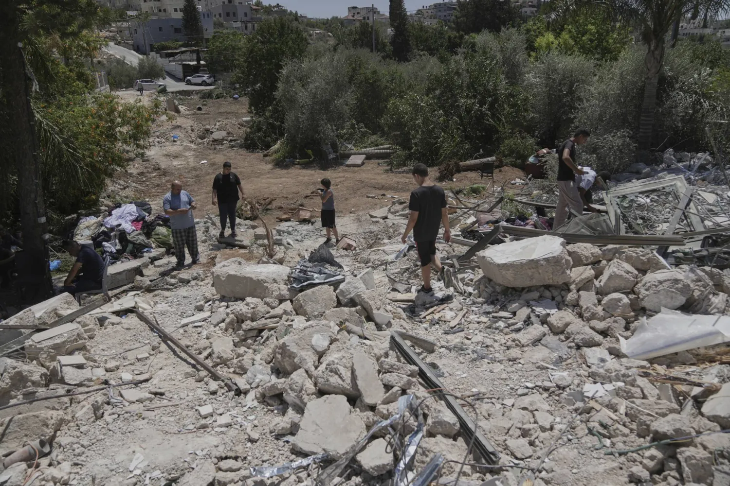 فلسطينيون يتفقدون أنقاض منزل بعد هدمه من قبل الجيش الإسرائيلي في قرية بيت سيرا بالضفة الغربية (أ.ب)