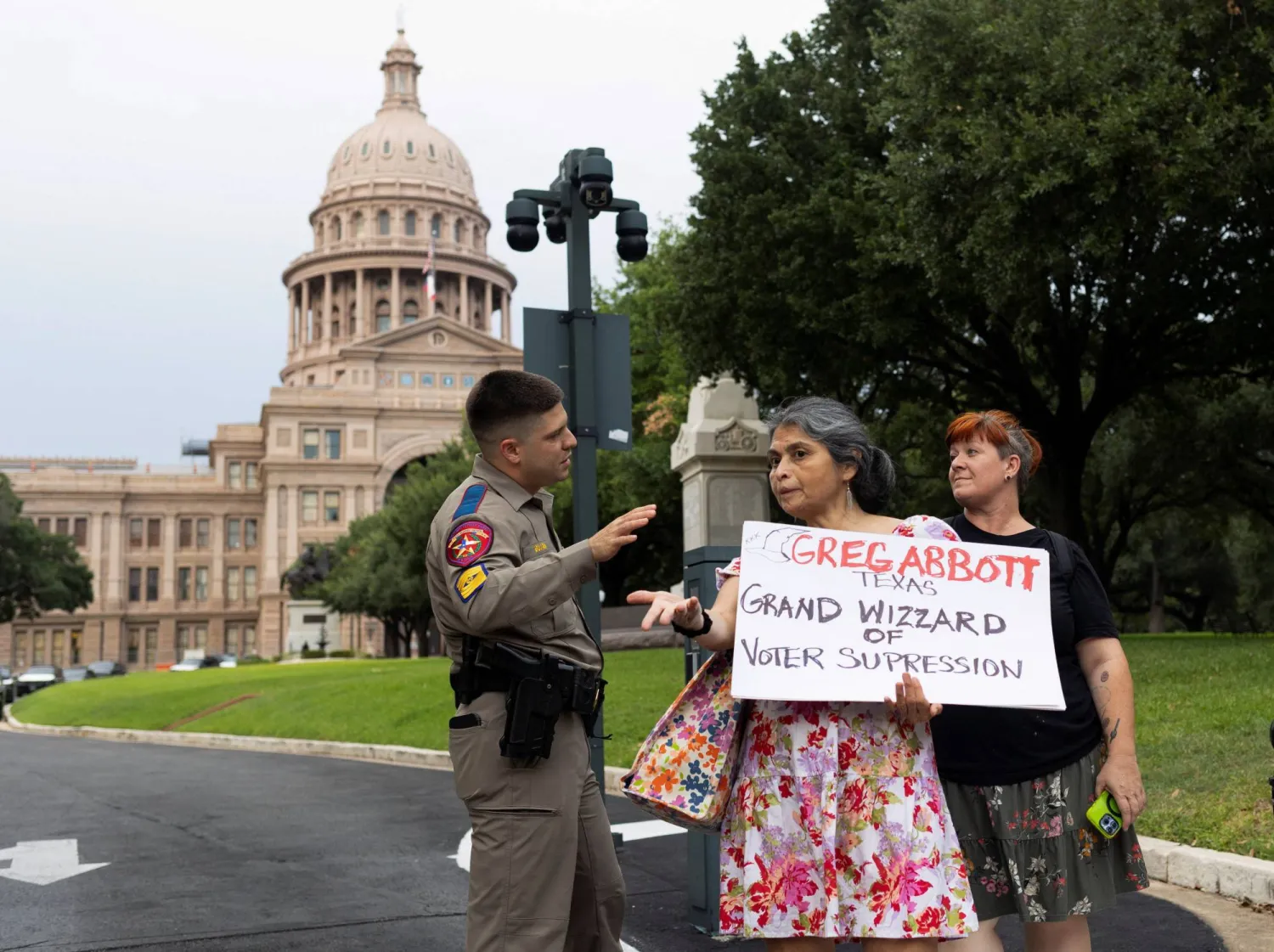 عنصر أمن يتناقش مع متظاهرتين خارج مقرّ «كابيتول تكساس» في أوستن يوم 19 أغسطس الحالي (رويترز)