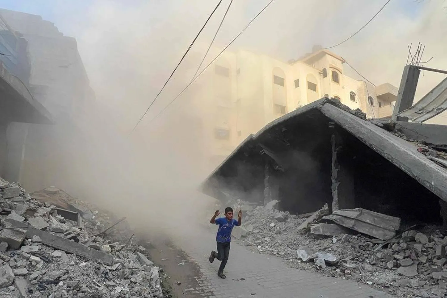 A Palestinian boy rushes away from the site of Israeli air strikes on a six-storey building in the Saftawi neighborhood west of Jabalia in the northern Gaza Strip on August 19, 2025. (AFP) 
