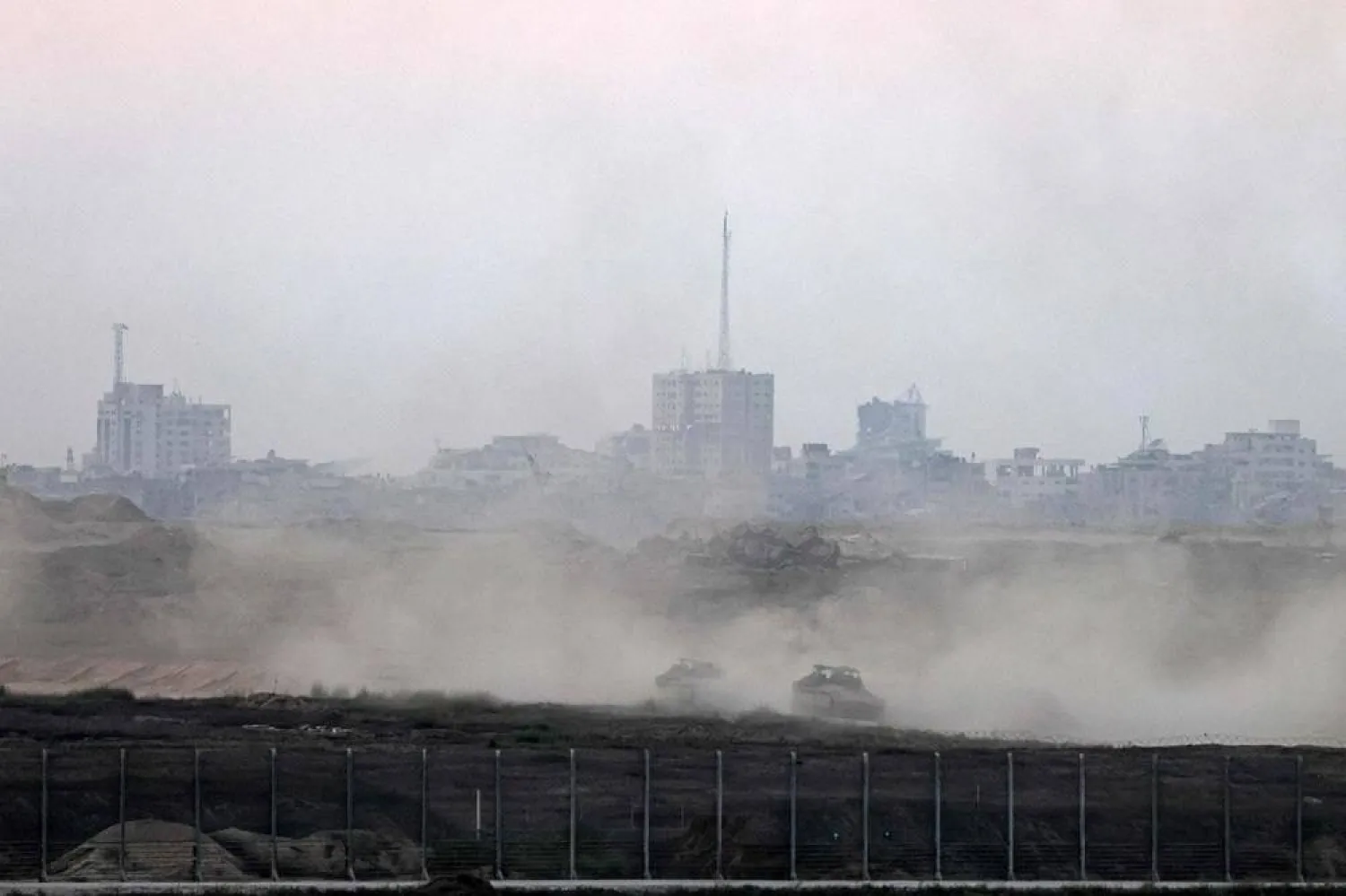  This picture taken from a position on the Israeli border with the Gaza Strip, shows Israeli armored personnel carriers driving behind the separation barrier on August 20, 2025. (AFP)