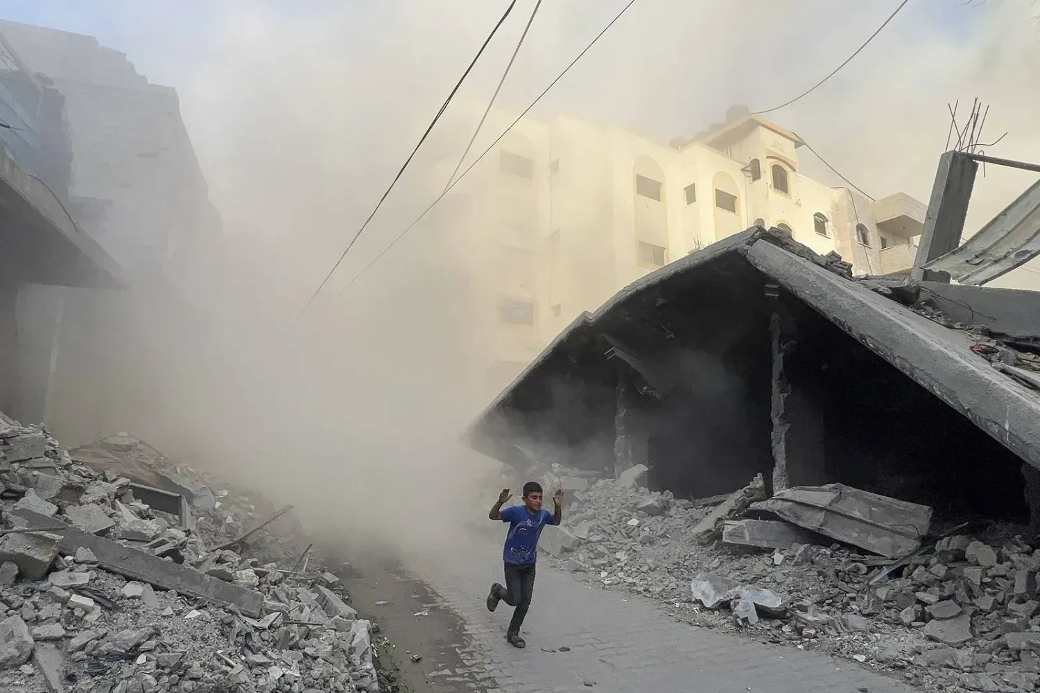 Filistinli bir çocuk, Gazze Şeridi'nin kuzeyindeki Cibaliye'nin batısındaki Saftavi semtinde İsrail hava saldırısının gerçekleştiği yerden kaçıyor (AFP)