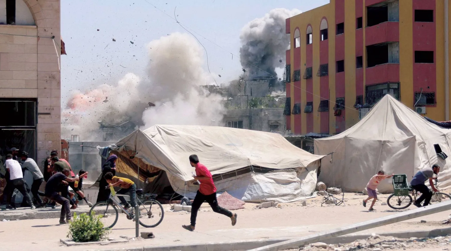  فلسطينيون يهرعون للاحتماء بعد غارة إسرائيلية على مبنى في جباليا شمال قطاع غزة أمس (أ.ف.ب)