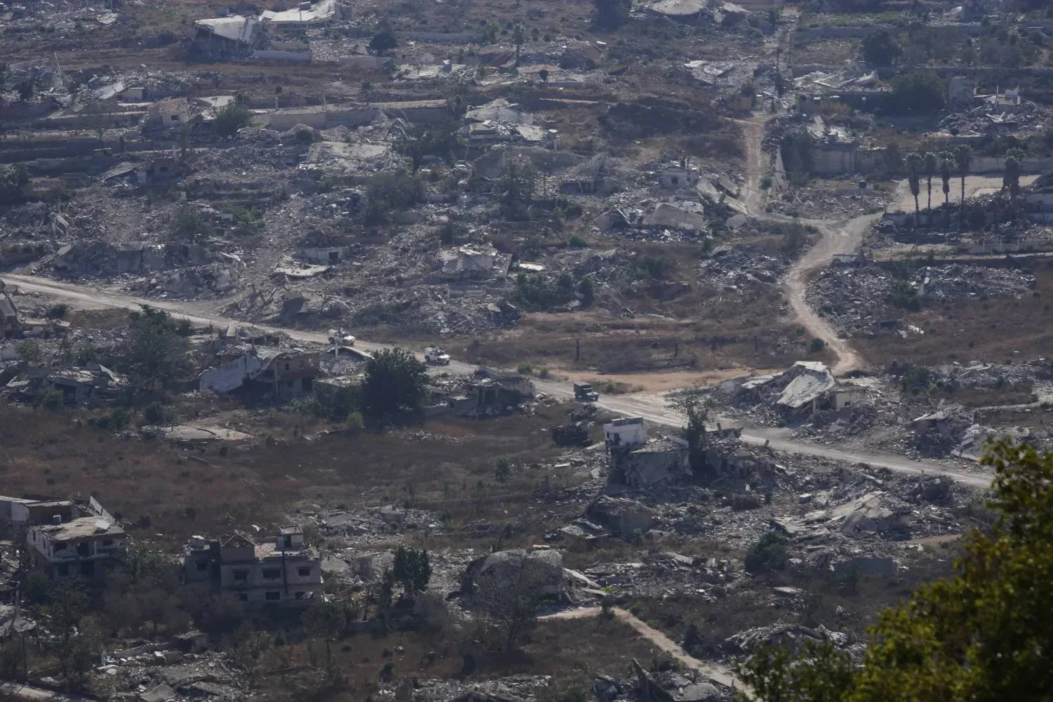 BM araçları, İsrail sınırına yakın Lübnan'ın Kfar Kila kasabasında yıkılmış bölgelerden geçiyor (AP)