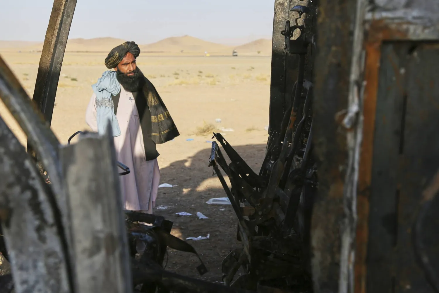 رجل ينظر إلى حافلة محترقة اصطدمت بشاحنة ودراجة نارية مساء الثلاثاء مما تسبب في حريق هائل ومقتل 70 شخصاً على الأقل بمن فيهم أطفال معظمهم أفغان عائدون من إيران في ولاية هرات الغربية... الأربعاء 20 أغسطس 2025 (أ.ب)