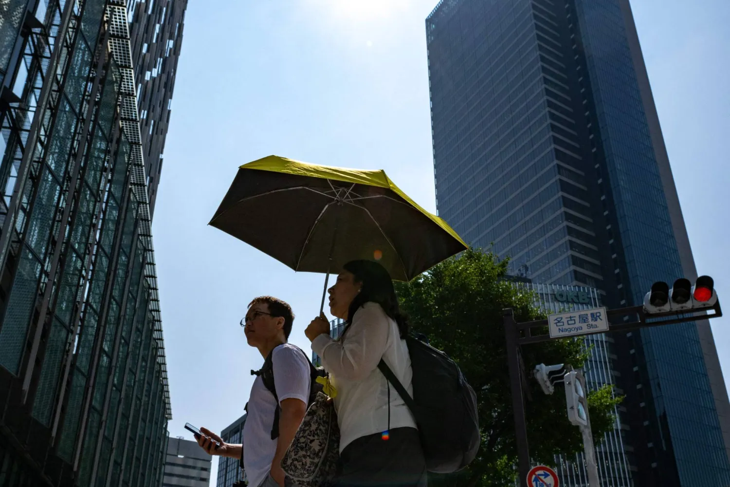 يابانيون يستخدمون المظلات وسط موجة حارة في أحد الأحياء التجارية بمدينة ناغويا (أ.ف.ب)