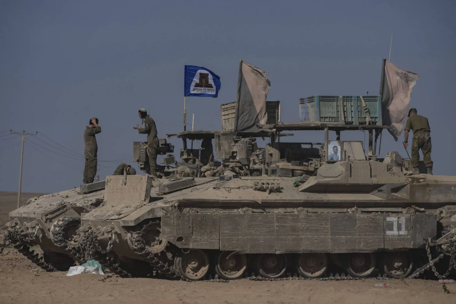 جنود إسرائيليون يقفون فوق مركبات مدرعة متوقفة في منطقة بالقرب من الحدود بين إسرائيل وغزة (أ.ب)