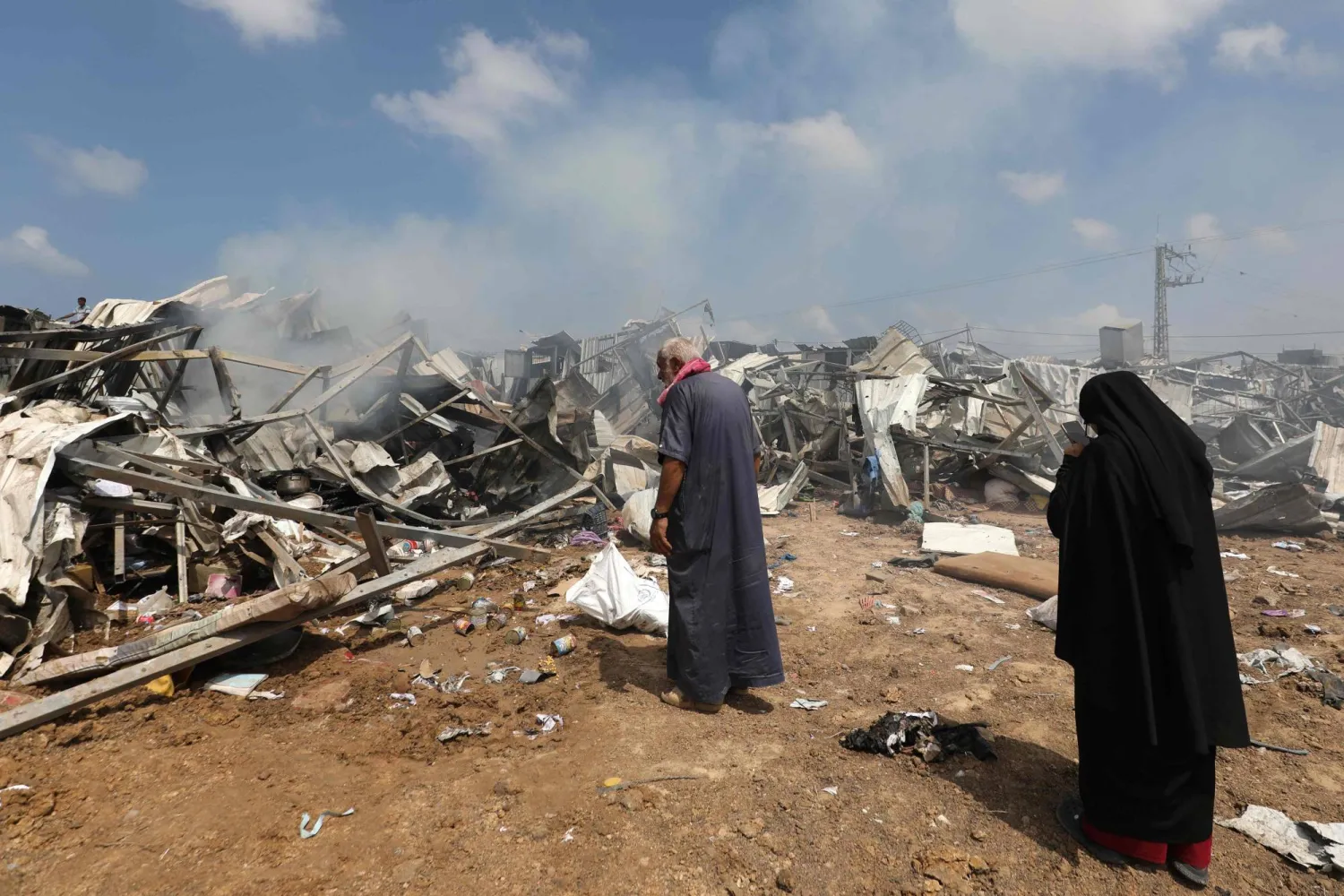 نازحون فلسطينيون يتفقدون الدمار الذي خلَّفته ضربة إسرائيلية على مخيم للنازحين في دير البلح وسط قطاع غزة الخميس (أ.ف.ب)