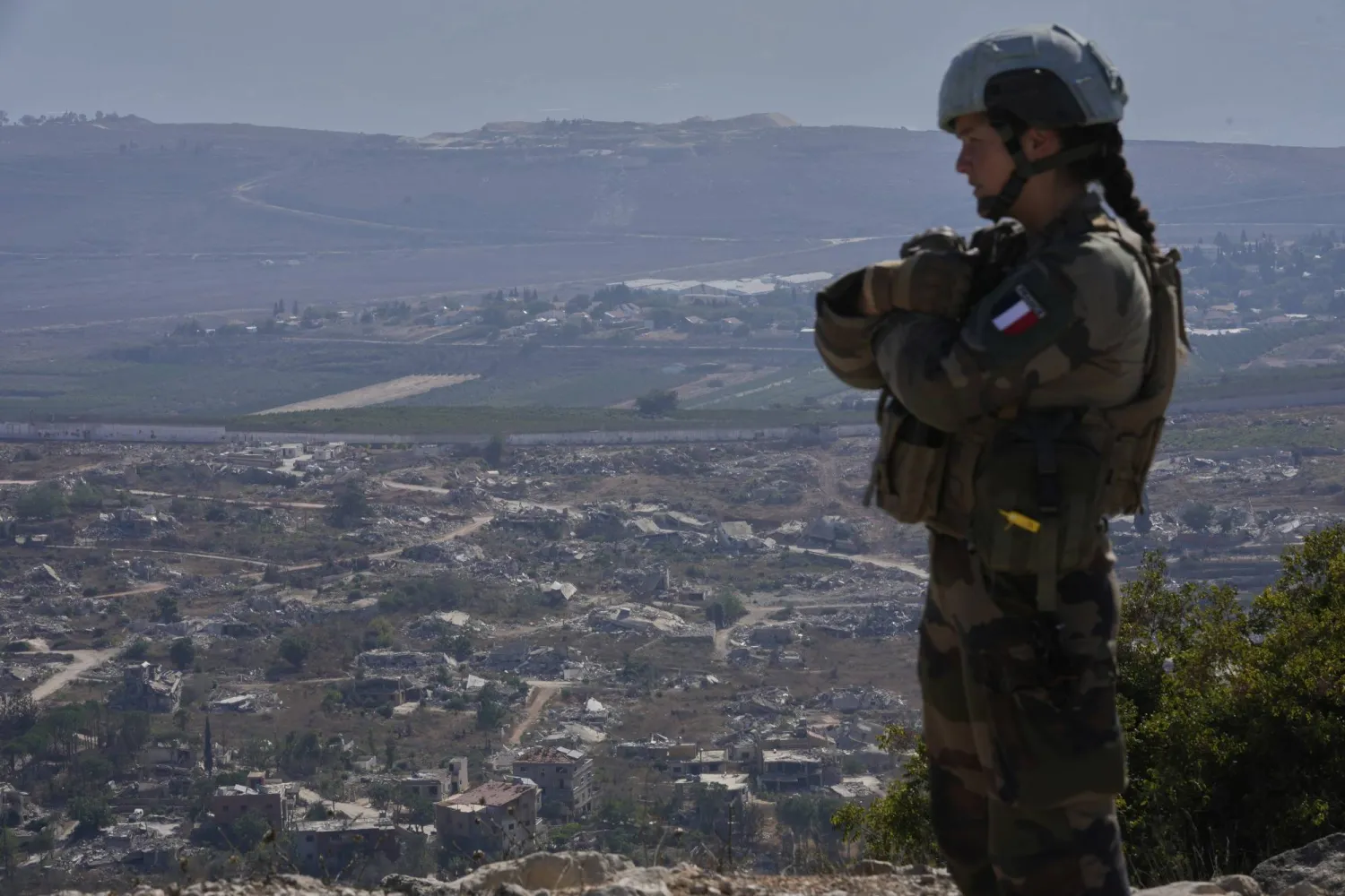 عنصر من الكتيبة الفرنسية في «يونيفيل» يقف على تلة مشرفة على بلدة كفركلا المدمرة بجنوب لبنان (أ.ب)