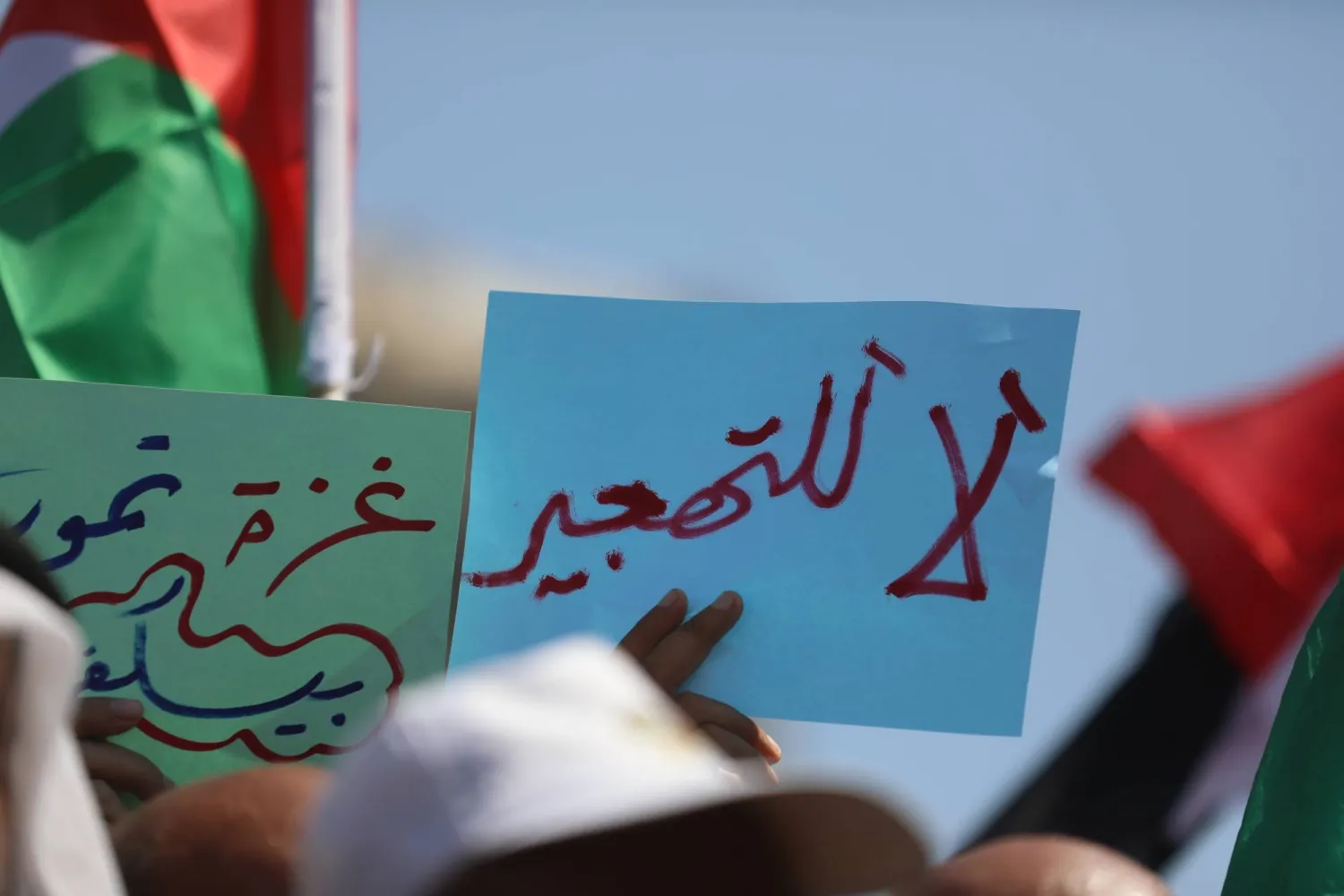 فلسطينيون يحملون لافتات كُتب عليها «لا للتهجير» و«غزة تموت» خلال احتجاج في مخيم النصيرات بغزة (د.ب.أ)