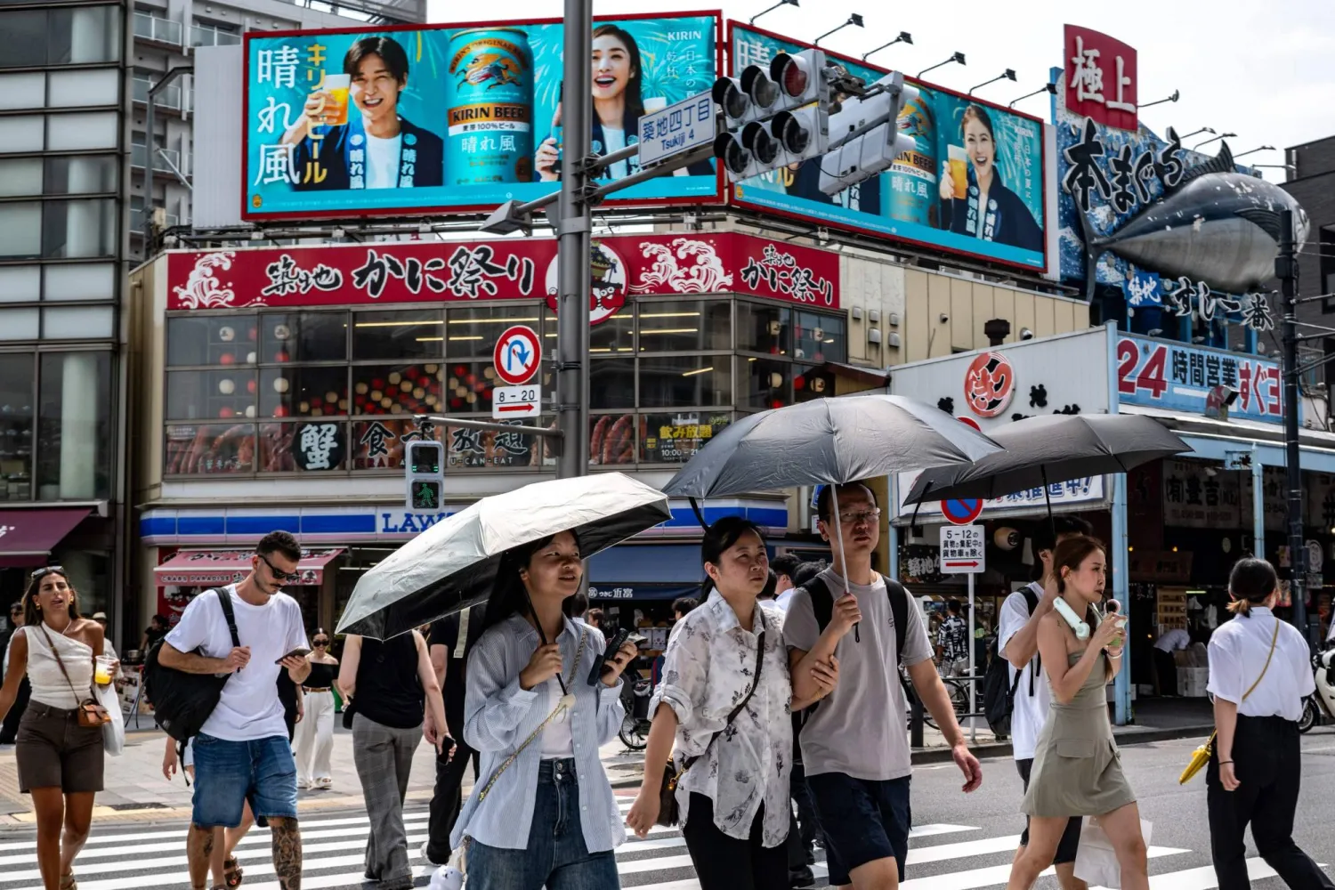 People walk across the street at the Tsukiji Outer Market in Tokyo on August 22, 2025. (Photo by Philip FONG / AFP)
