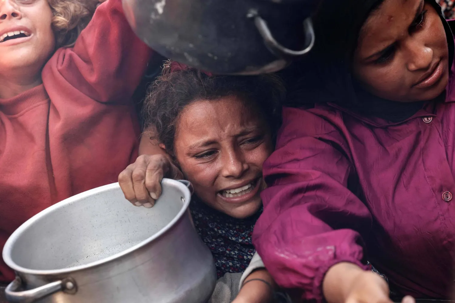 أطفال فلسطينيون يحملون أوانيهم الفارغة أمام مطبخ خيري في خان يونس جنوب قطاع غزة أمس (أ.ف.ب)