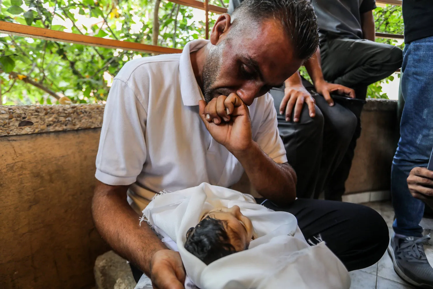 فلسطيني ينظر إلى ابنته (5 أشهر) التي توفيت جراء سوء التغذية في خان يونس جنوب قطاع غزة الجمعة (د.ب.أ)