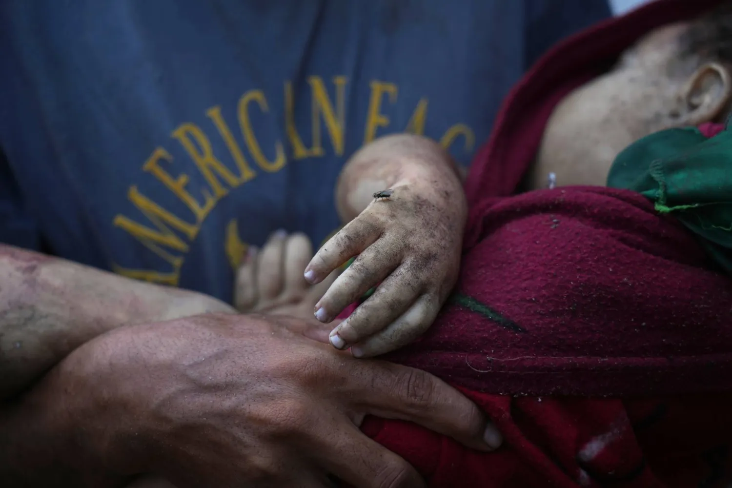 فلسطيني يحمل جثة طفلة (4 سنوات) قُتلت بقصف إسرائيلي استهدف مدرسة تؤوي نازحين في مدينة غزة الجمعة (أ.ب)