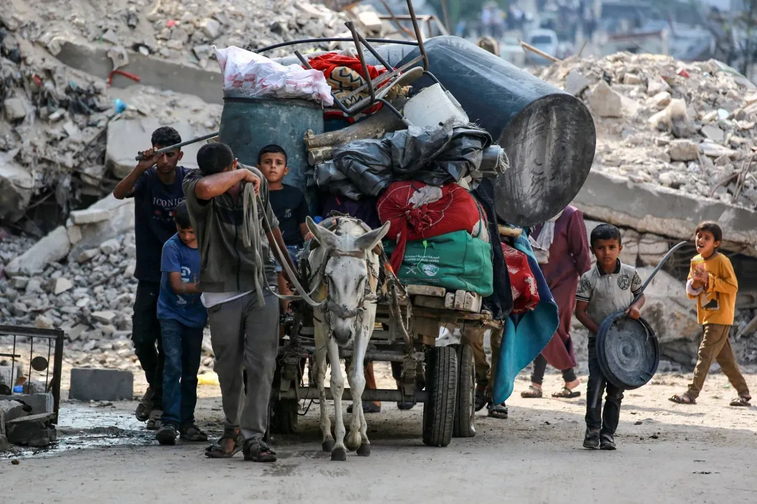 Gazze şehrinin kuzeyindeki Ebu İskender mahallesinden ayrılırken eşyalarını eşek arabasıyla taşıyan Filistinliler (AFP)