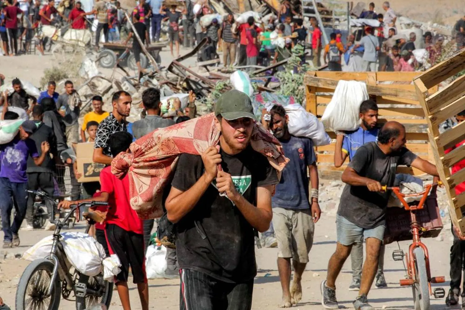 People walk with bags of humanitarian aid they received at a distribution center run by the US and Israeli-backed Gaza Humanitarian Foundation (GHF), as they cross the so-called "Netzarim corridor" in the central Gaza Strip, on August 22, 2025. (AFP)