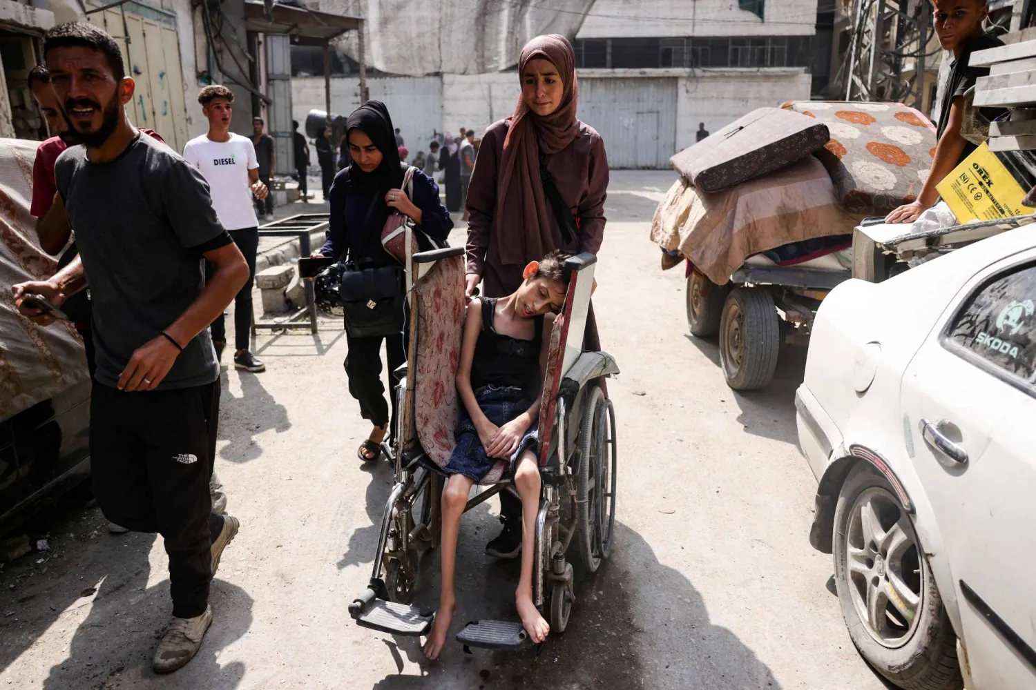 فلسطينية تجر كرسياً متحركاً عليه طفلها المصاب بسوء تغذية خلال مغادرة منطقة أبو إسكندر شمال مدينة غزة باتجاه مكان آمن الجمعة (أ.ف.ب)