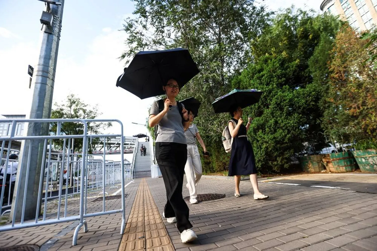 People walk near fences on a street in Beijing, China, 22 August 2025. (EPA) 
