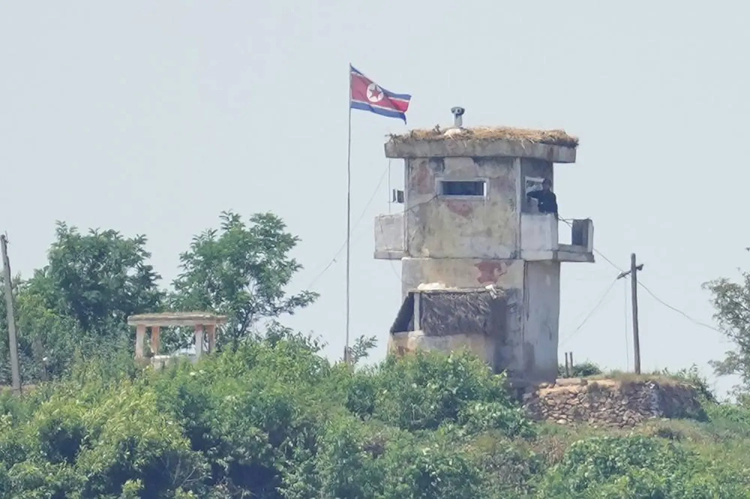 A soldier stands at a North Korean military guard post flying a national flag, seen from Paju, South Korea, June 26, 2024. (AP)