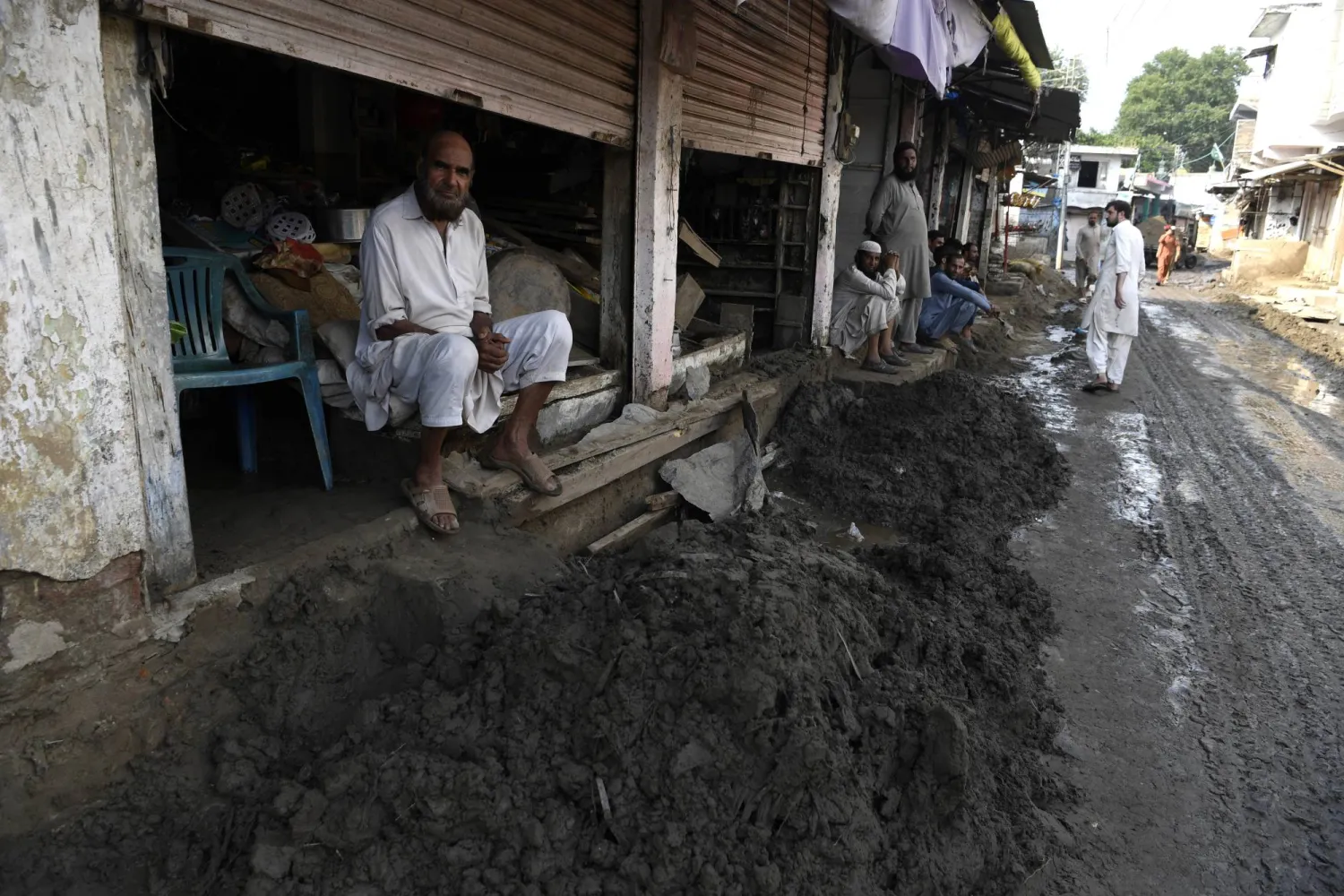 People sit along a mud-covered road as rescue operations continue after flash floods in Buner, Khyber Pakhtunkhwa province, Pakistan, 22 August 2025. EPA/SOHAIL SHAHZAD