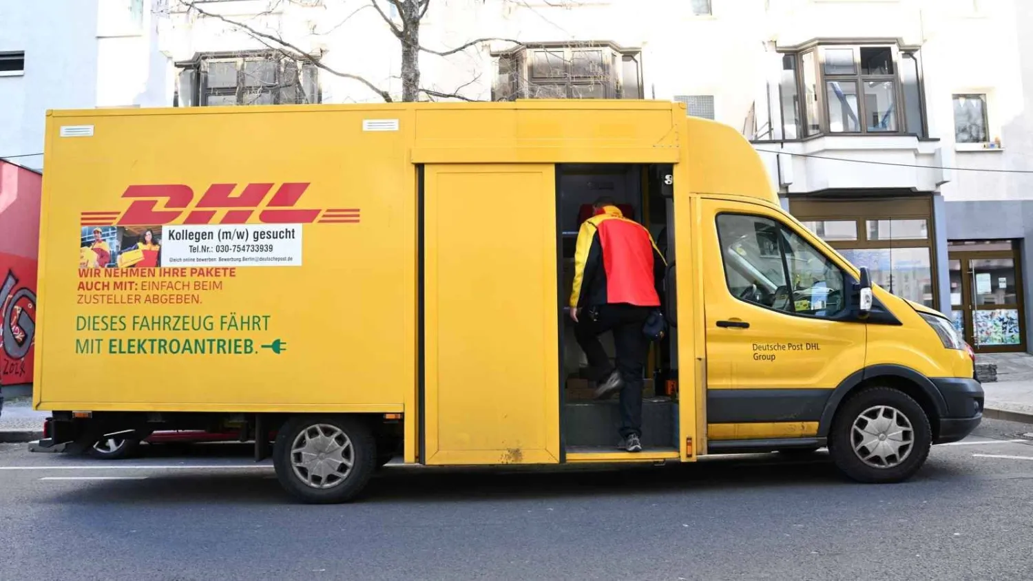 عامل يدخل مركبة تابعة لمجموعة «دي إتش إل» في برلين (رويترز)