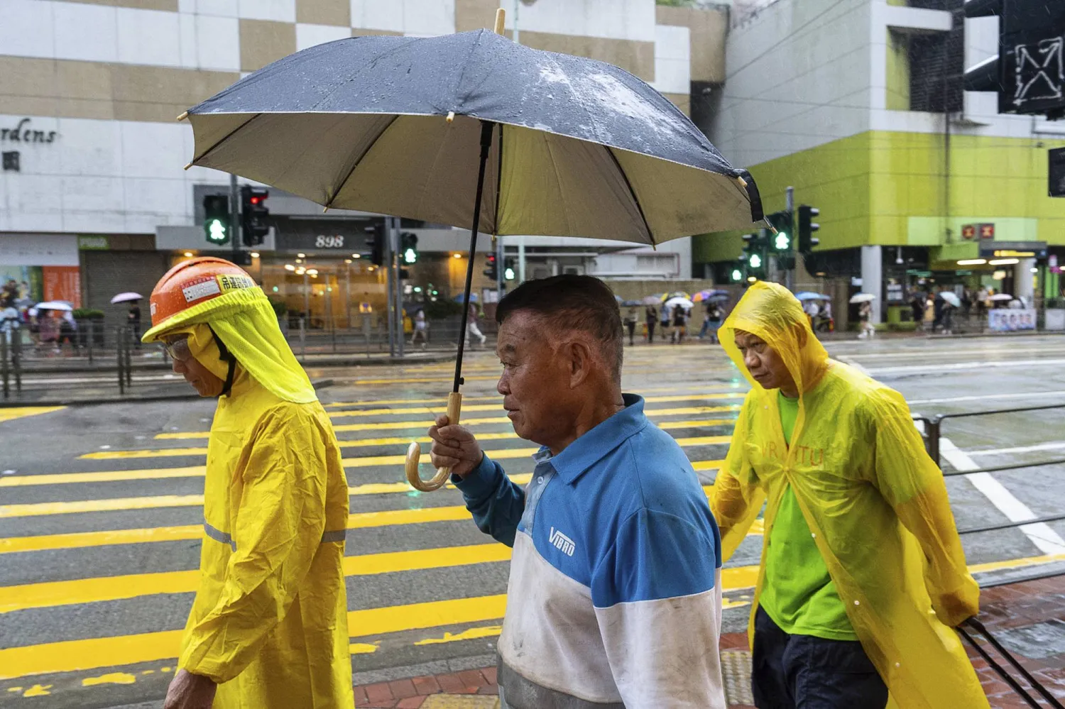 أشخاص يحملون مظلات في هونغ كونغ تحت المطر بينما كانت العاصفة الاستوائية «بودول» تبتعد عن المدينة التي تتمتع بحكم ذاتي جزئي (أ.ب)