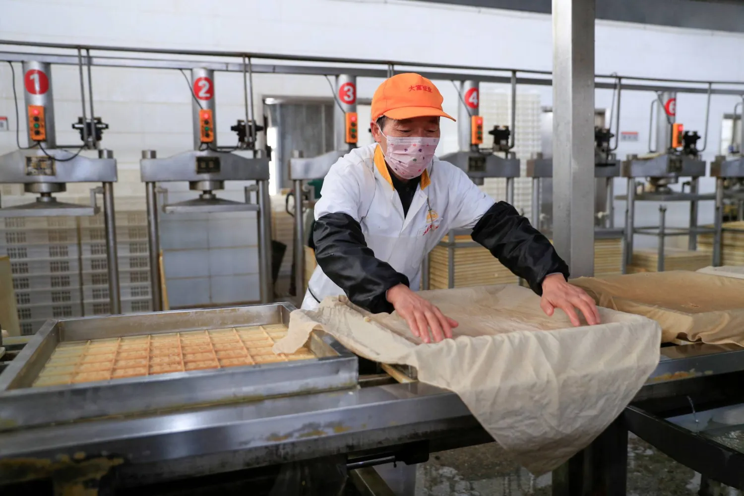 FILE PHOTO: A worker wearing a face mask works on a production line manufacturing soybean-based food products at a factory in Hefei, Anhui province, China February 4, 2020. China Daily via REUTERS 