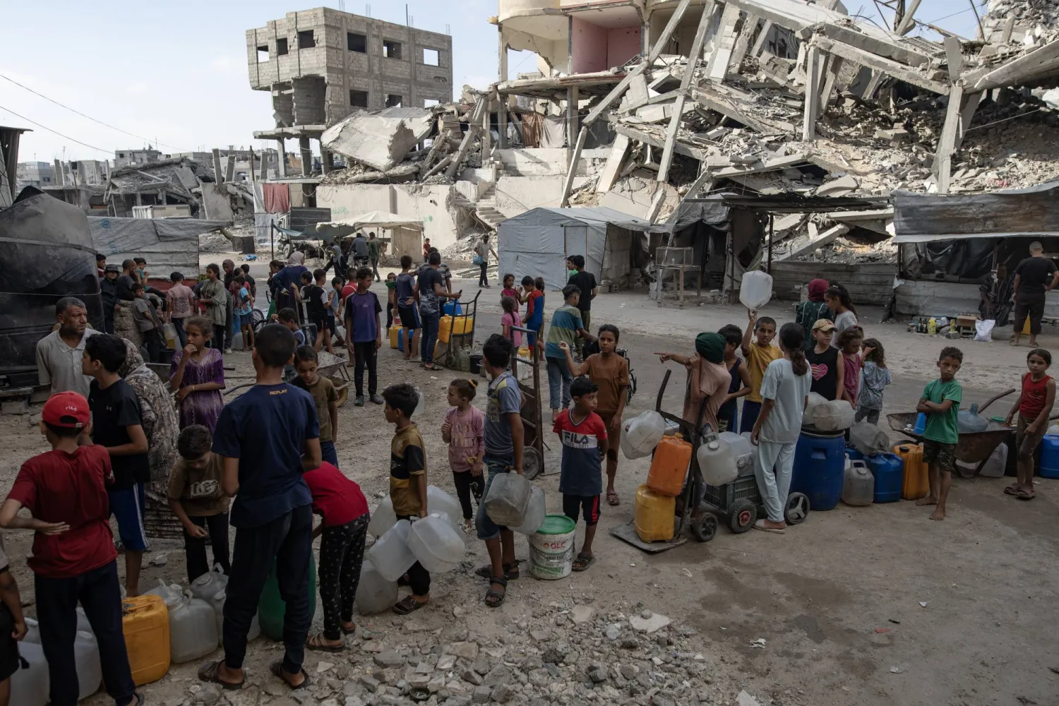 نازحون فلسطينيون يصطفون للحصول على المياه من عربة توزيع في خان يونس جنوب قطاع غزة (إ.ب.أ) 