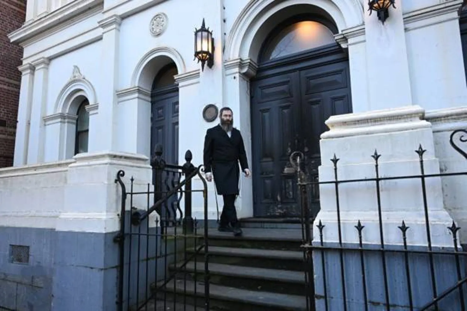 حاخام أمام باب كنيس يهودي تظهر عليه علامات حريق في ملبورن (الأوروبية)