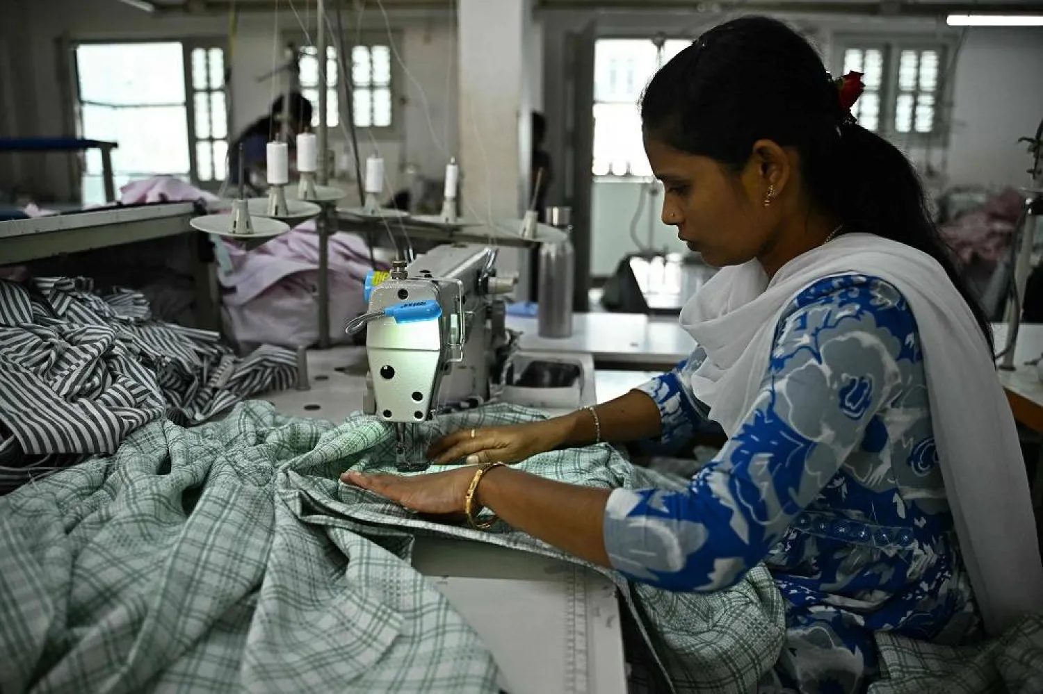 A garment worker tailors clothes on a sewing machine at an apparel manufacturing unit in Bengaluru on August 25, 2025. (AFP)