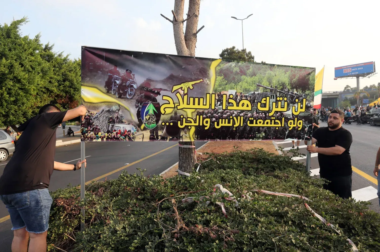 Beyrut Havaalanı’na giden yolda Hizbullah’ın silahlarını teslim etmesini reddettiklerini belirten bir pankart açan Hizbullah destekçileri (EPA)