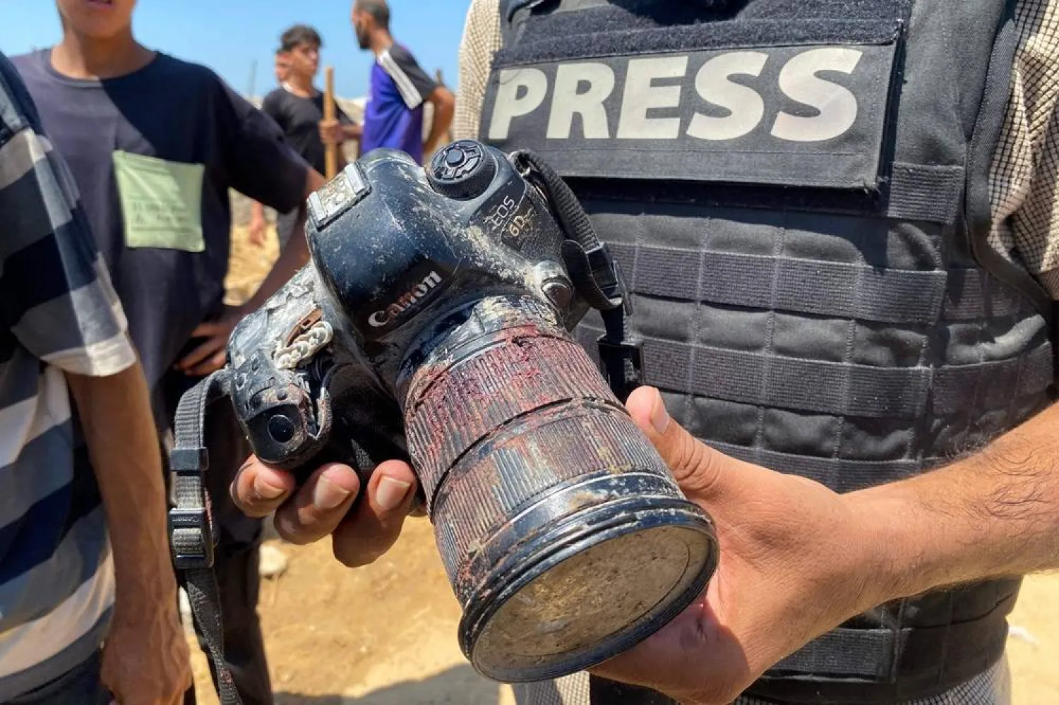 A journalist holds a blood-covered camera belonging to Palestinian photojournalist Hussam al-Masri, a Reuters contractor who was killed in an Israeli strike on Nasser hospital in Khan Younis in the southern Gaza Strip, during his funeral on August 25, 2025. (AFP)